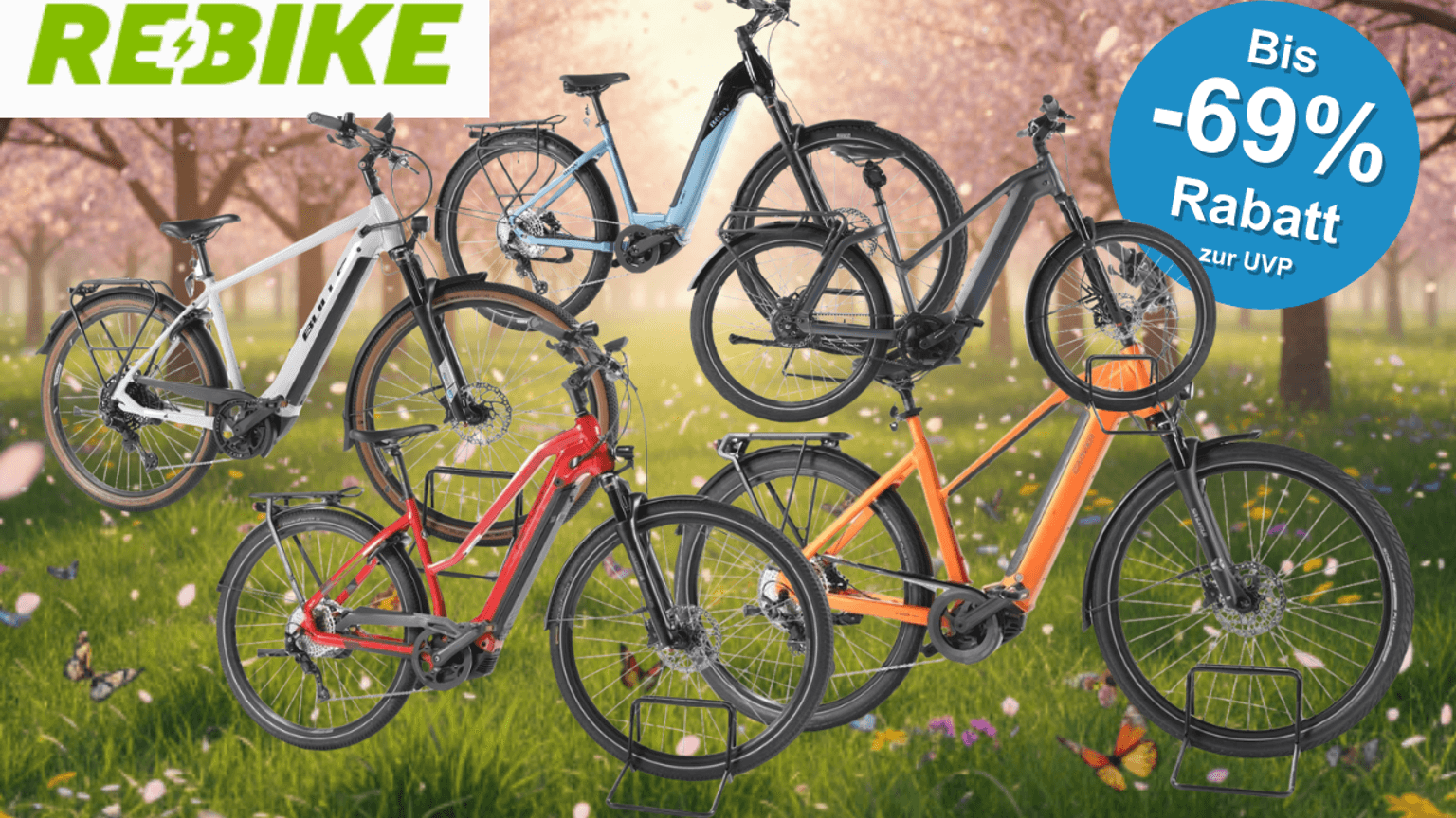 E-Bikes Trekking, City und E-Mountain-Bikes verschiedener Marken vor einer grünen Wiese mit bunten Blumen und blühenden Bäumen.