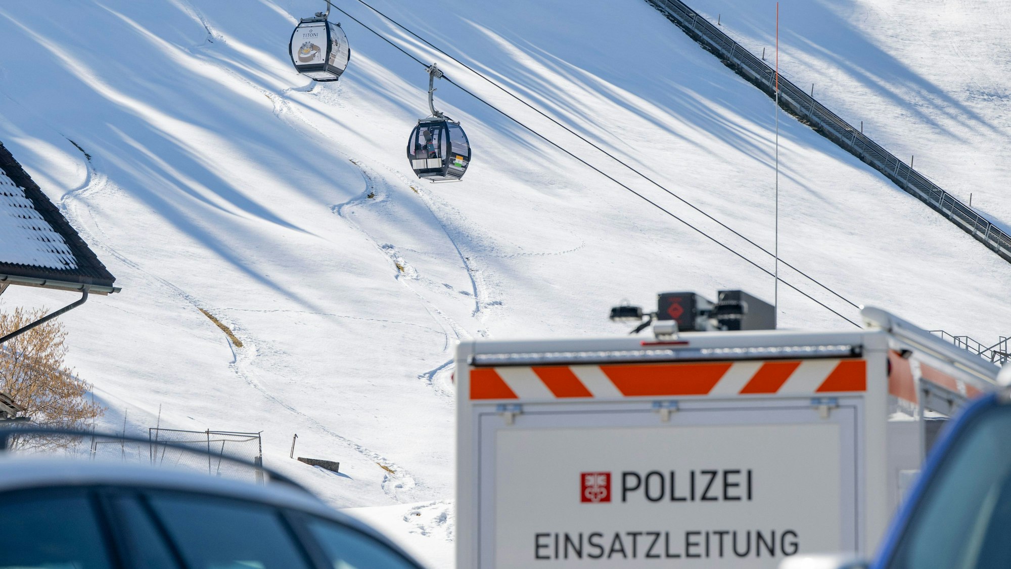 18.03.2026, Schweiz, Engelberg: Ein Einsatzfahrzeug der Polizei steht bei der Talstation der Titlisbahnen. Im Hintergrund sind zwei Gondeln der Gondelbahn Engelberg-Titlis Express zu sehen. Im Schweizer Skigebiet Engelberg ist eine Gondel abgestürzt. Foto: Urs Flueeler/KEYSTONE/dpa +++ dpa-Bildfunk +++
