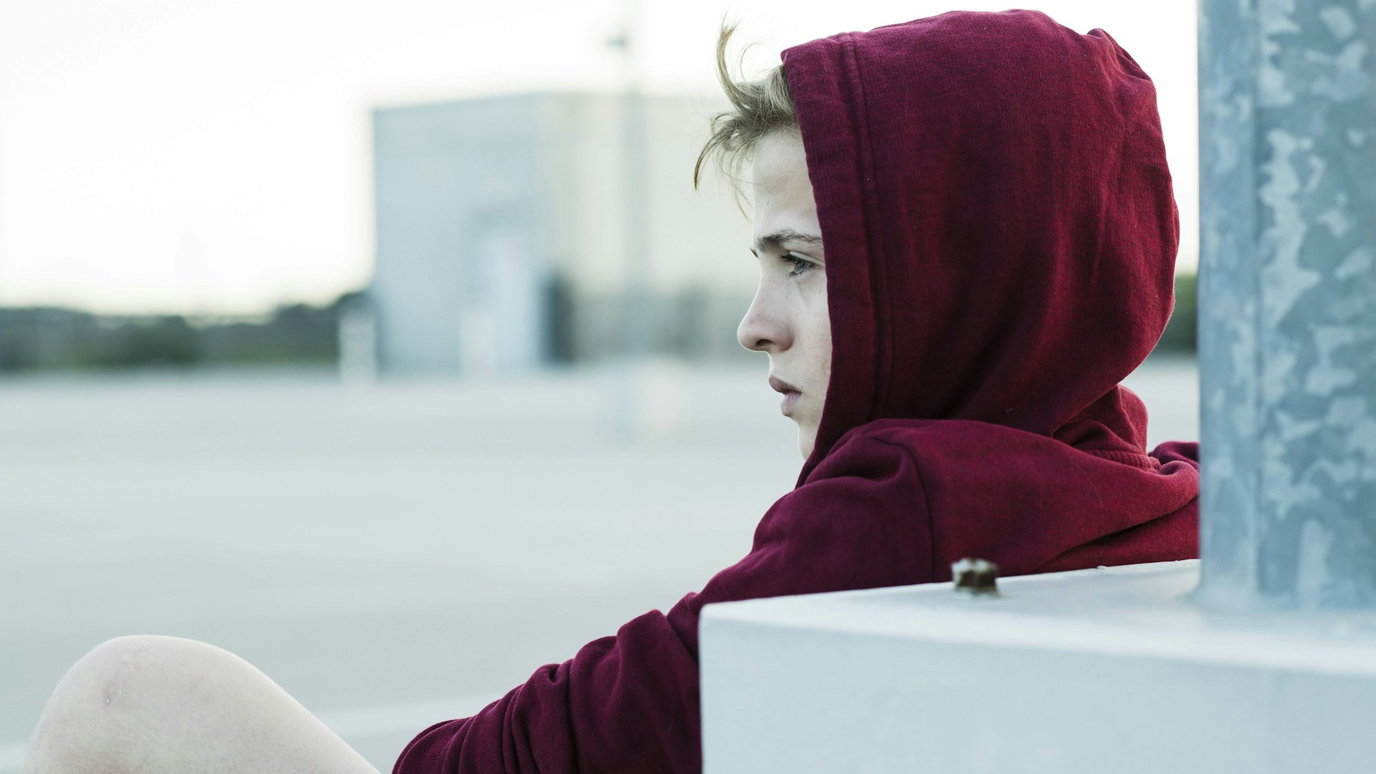 Jugendlicher mit ernster Miene sitzt draußen.