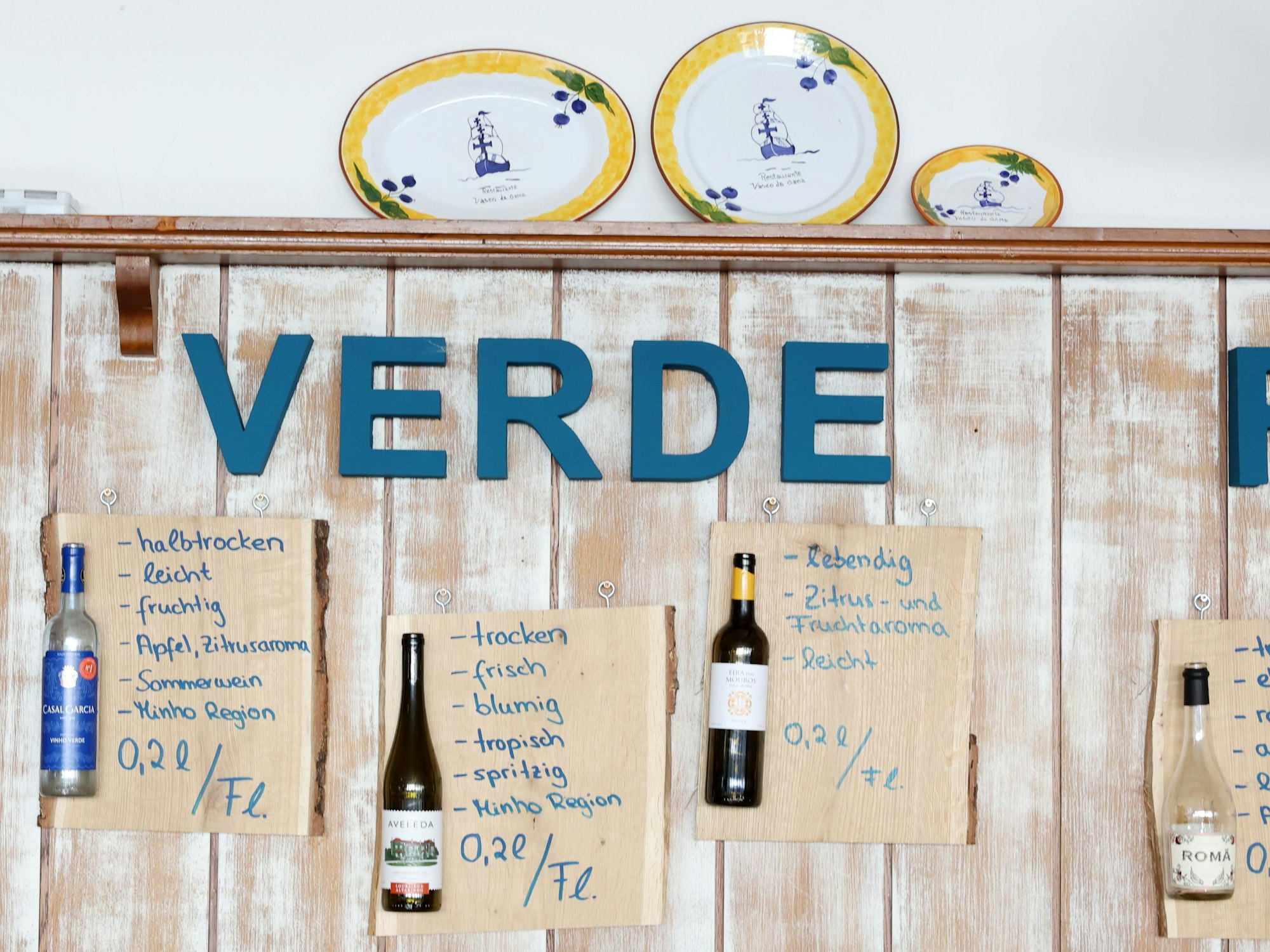 Leere Weinflaschen hängen auf Kartons an der Wand - dort ist die Charakteristik der Weine aufgeführt, etwa „trocken und blumig“ oder „halbtrocken und leicht“.
