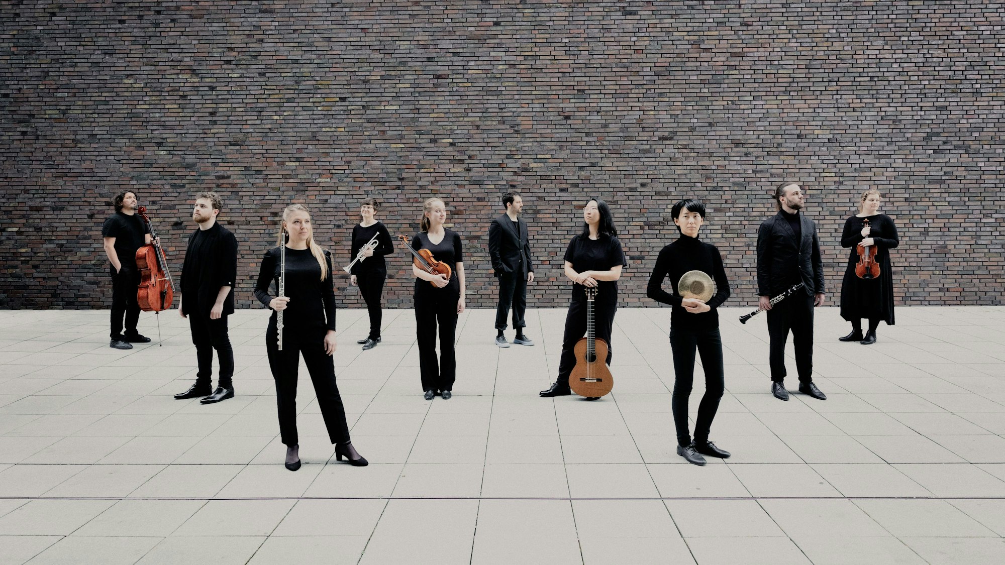 Musikerinnen und Musiker stehen, größtenteils mit Instrumenten in den Händen, nebeneinander.