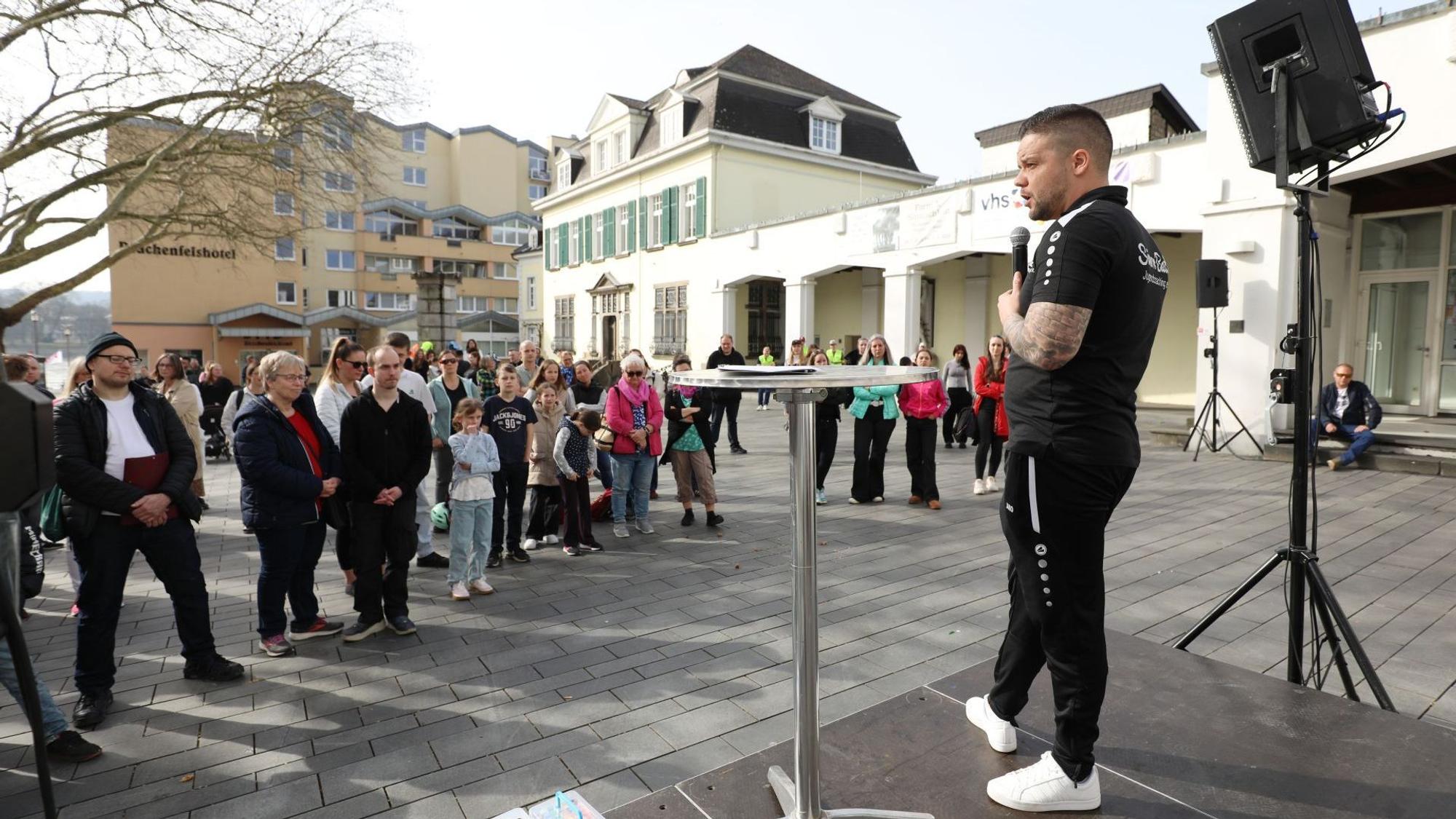 Teilnehmer einer Kundgebung auf dem Marktplatz, auf einer Bühne ein Mann mit Mikro.