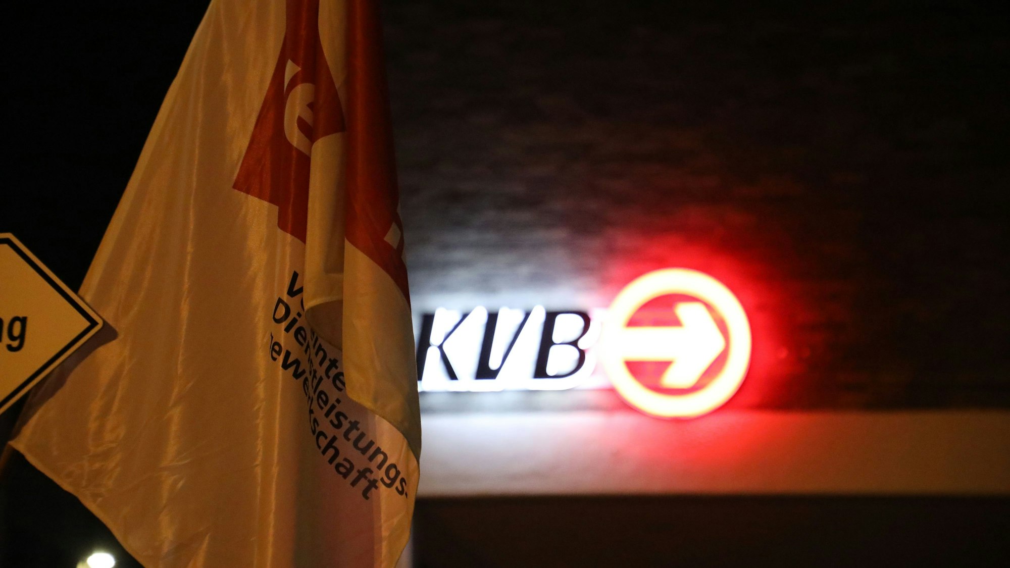 Eine Flagge von Verdi hängt vor einem Logo der KVB. In der Tarifrunde für den kommunalen Nahverkehr hat Verdi erneut zu Warnstreiks aufgerufen.