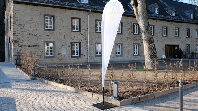 Ein altes Haus aus Bruchstein. davor eine alte Platane und eine weiße Fahne.