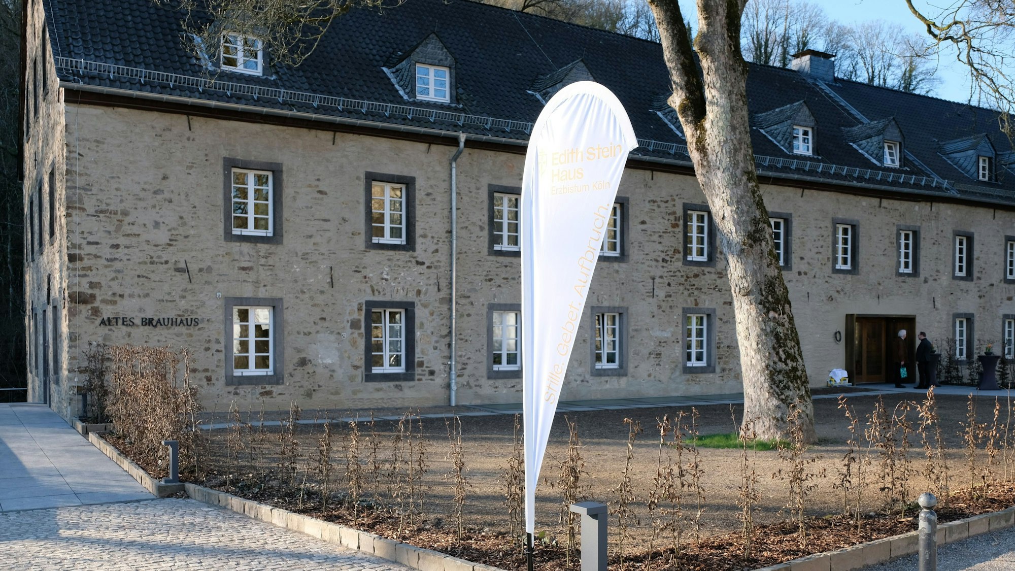 Ein altes Haus aus Bruchstein. davor eine alte Platane und eine weiße Fahne.