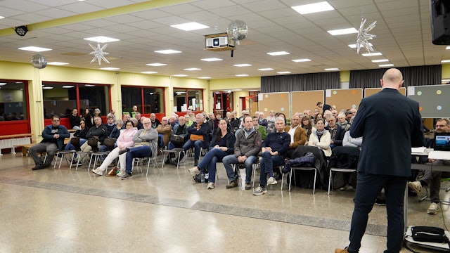 Die Aufnahme zeigt die sitzenden Teilnehmer in einem Saal der Gemünder Grundschule. Vor ihnen steht, von hinten fotografiert, Bürgermeister Ingo Pfennings.