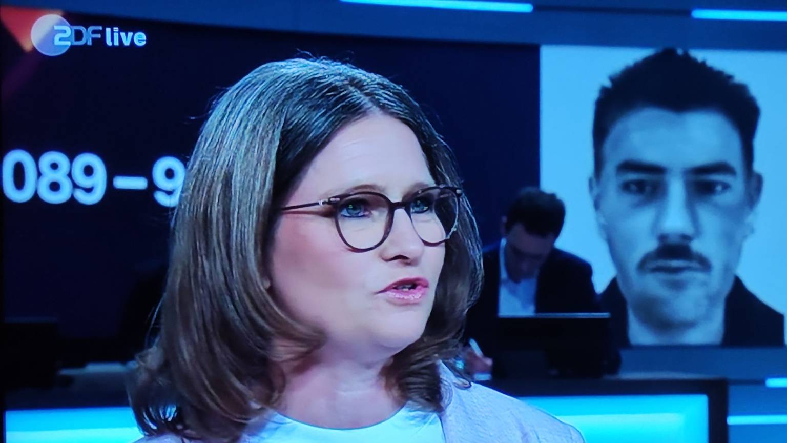 Jessica Scheer-Thielen steht im Fernsehstudio, rechts hinter ihr ist ein Phantombild des Täters eingeblendet.