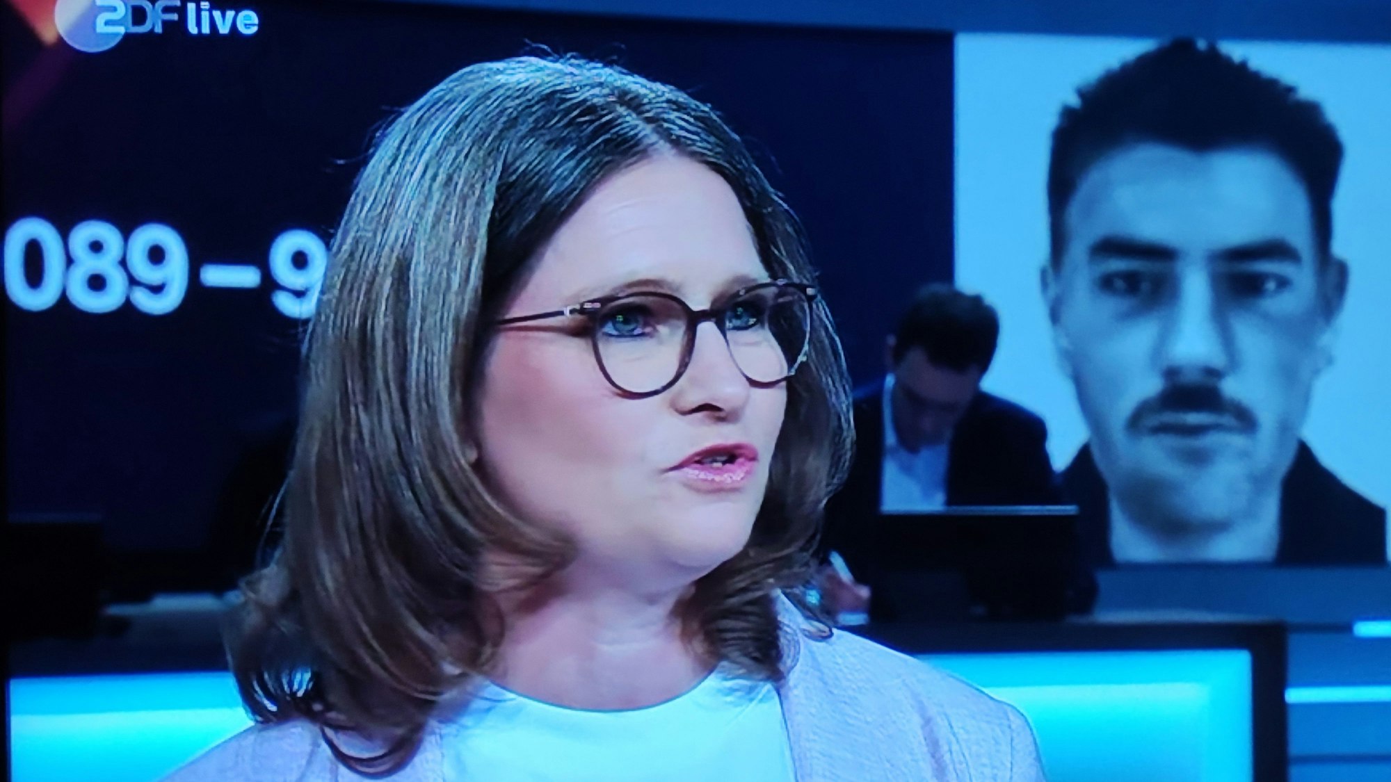 Jessica Scheer-Thielen steht im Fernsehstudio, rechts hinter ihr ist ein Phantombild des Täters eingeblendet.