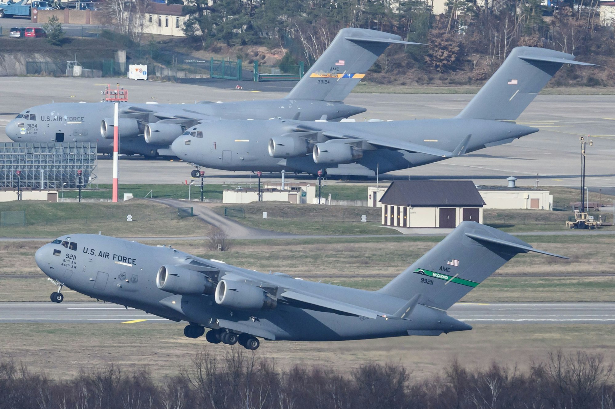 Eine Boeing C-17 Globemaster III der U.S. Air Force startet von der US-Airbase Ramstein, während weitere Militärtransportflugzeuge desselben Typs auf dem Vorfeld stehen.