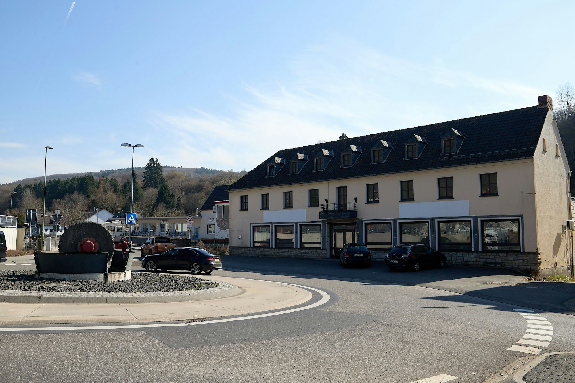 Vor einem großen, offensichtlich leerstehden Haus befindet sich ein Kreisverkehr.