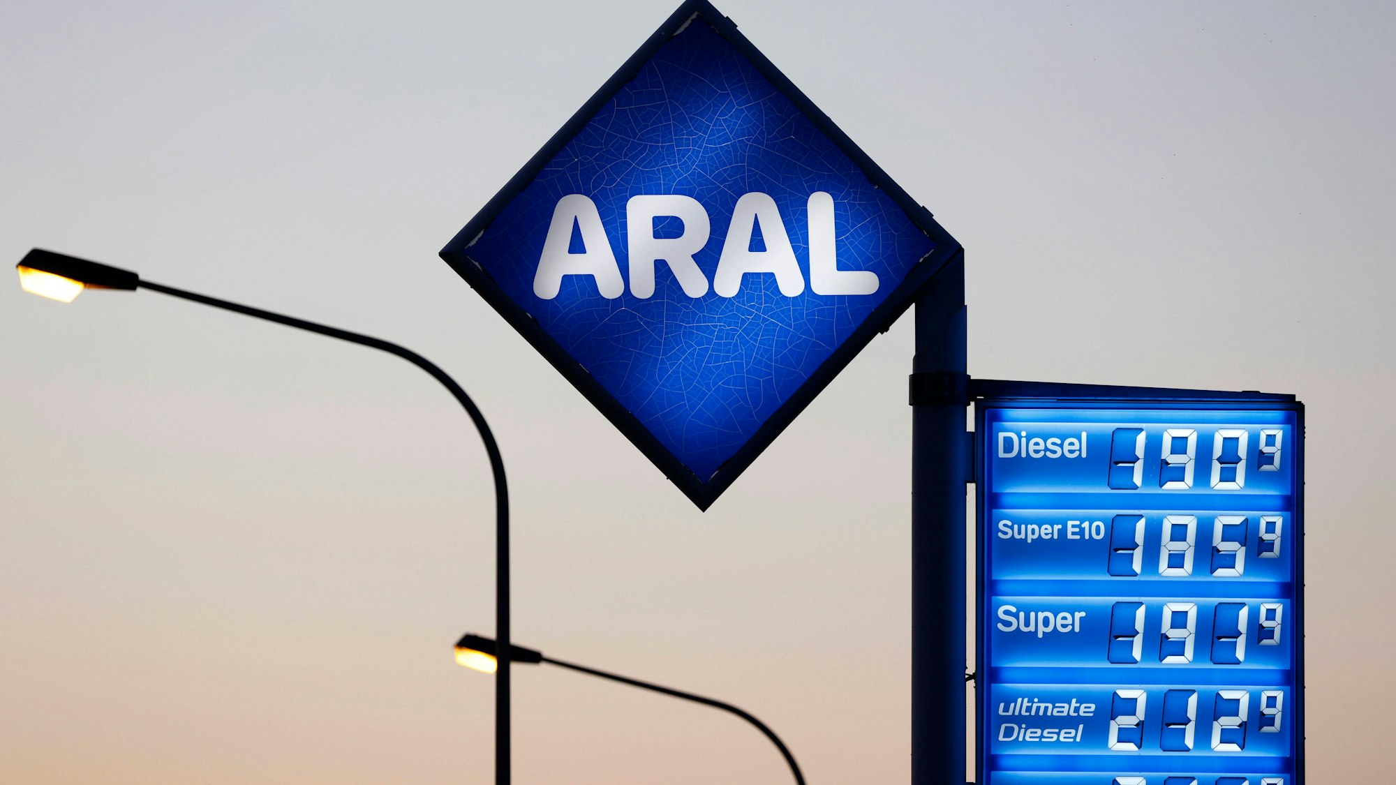 Tankstellenanzeige mit Preisen und Straßenlaternen