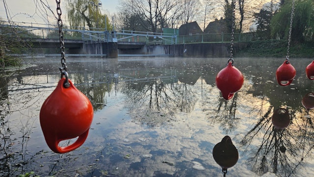 Die Erft in Bedburg: Im Hintergrund ein Wehr, im Vordergrund Rettungsbojen.