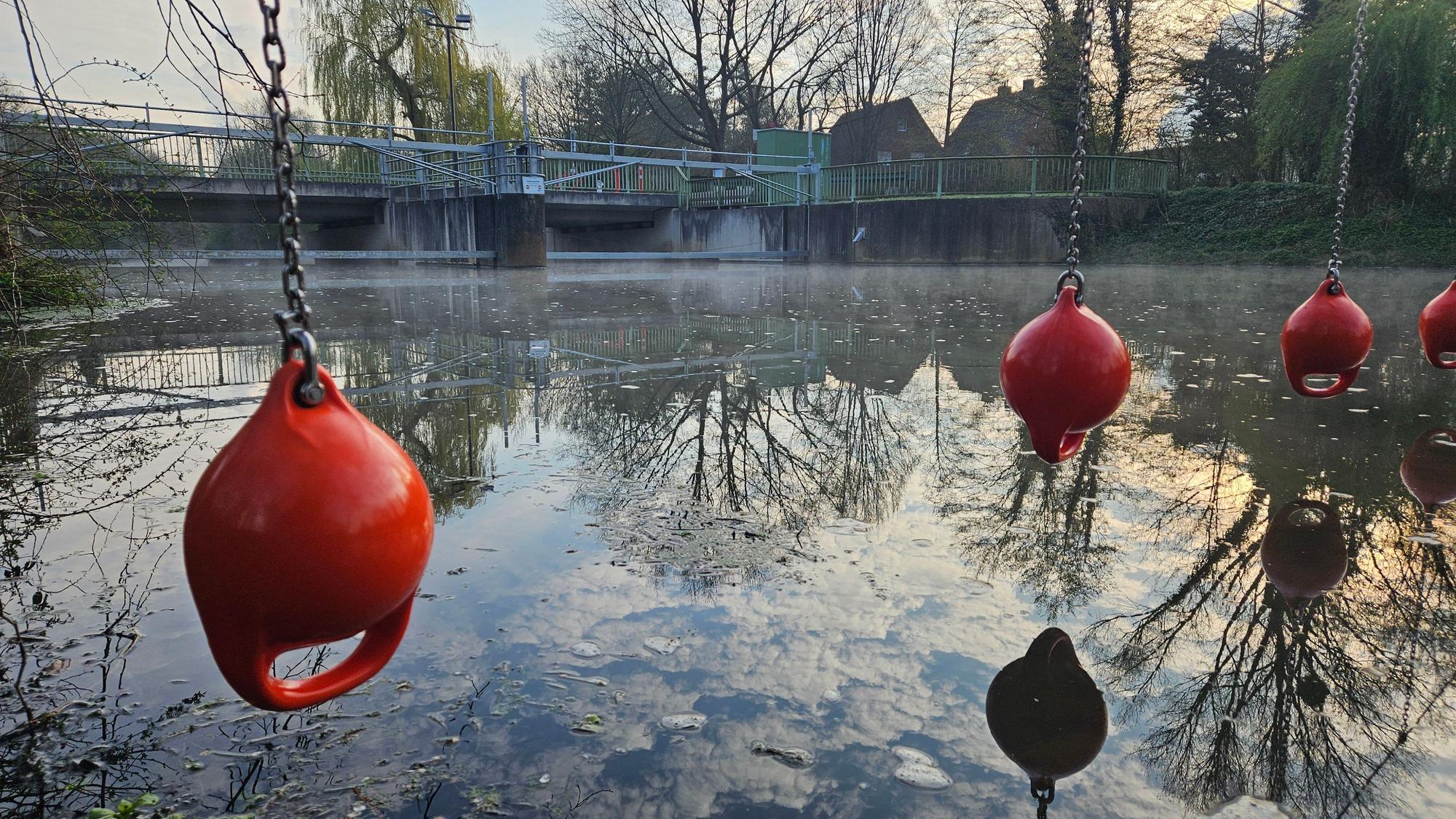 Die Erft in Bedburg: Im Hintergrund ein Wehr, im Vordergrund Rettungsbojen.