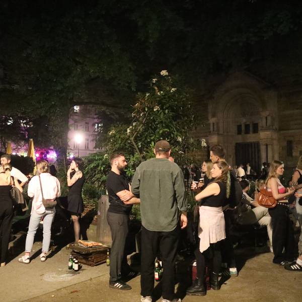 Das Bild zeigt die Situation auf dem Brüsseler Platz im April 2025: Menschen treffen und unterhalten sich, manche halten dabei ein Getränk.