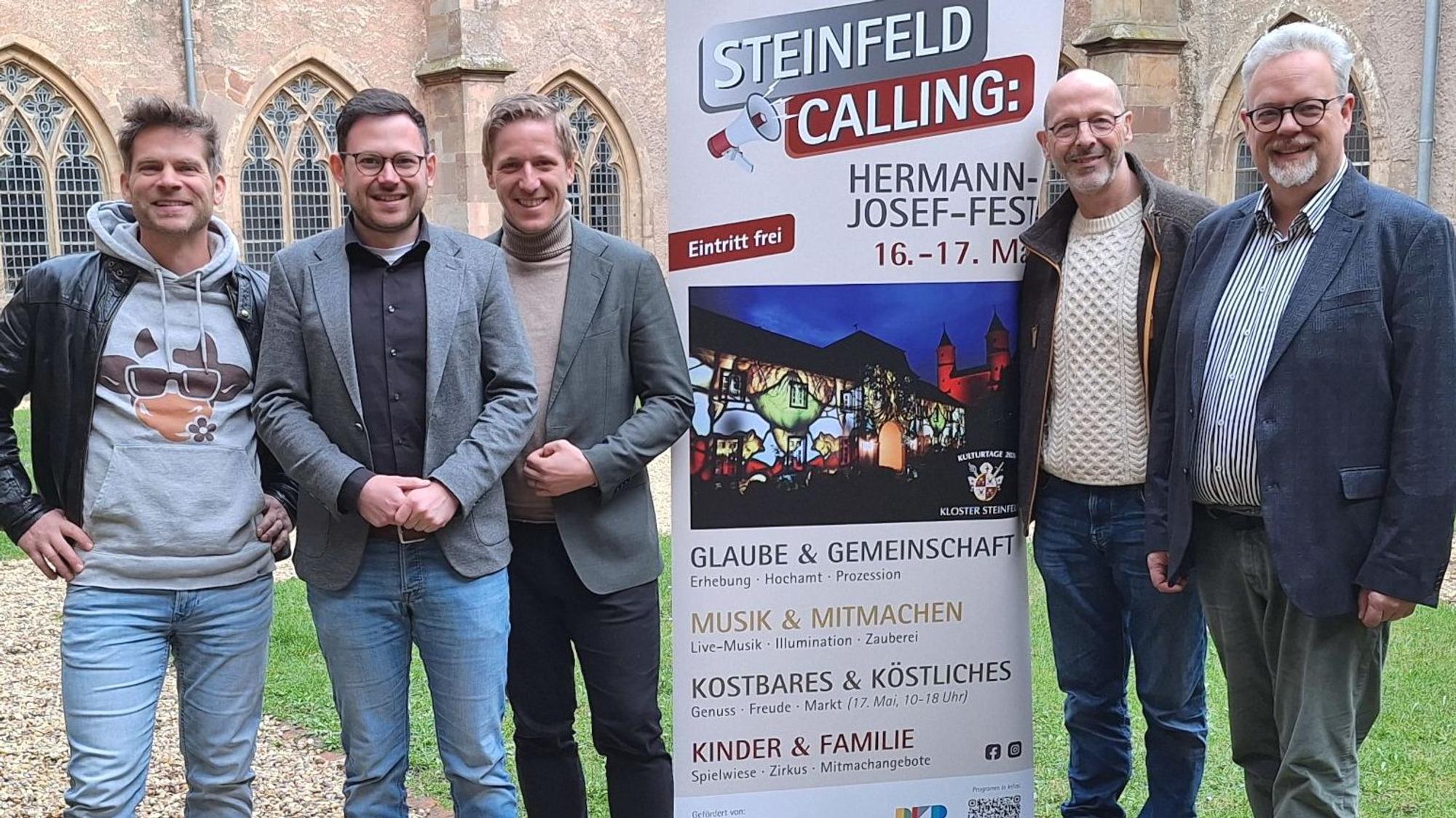Die Obengenannten stehen vor der Basilika, zwischen ihnen wird auf einem Aufsteller für Steinfeld Calling geworben.