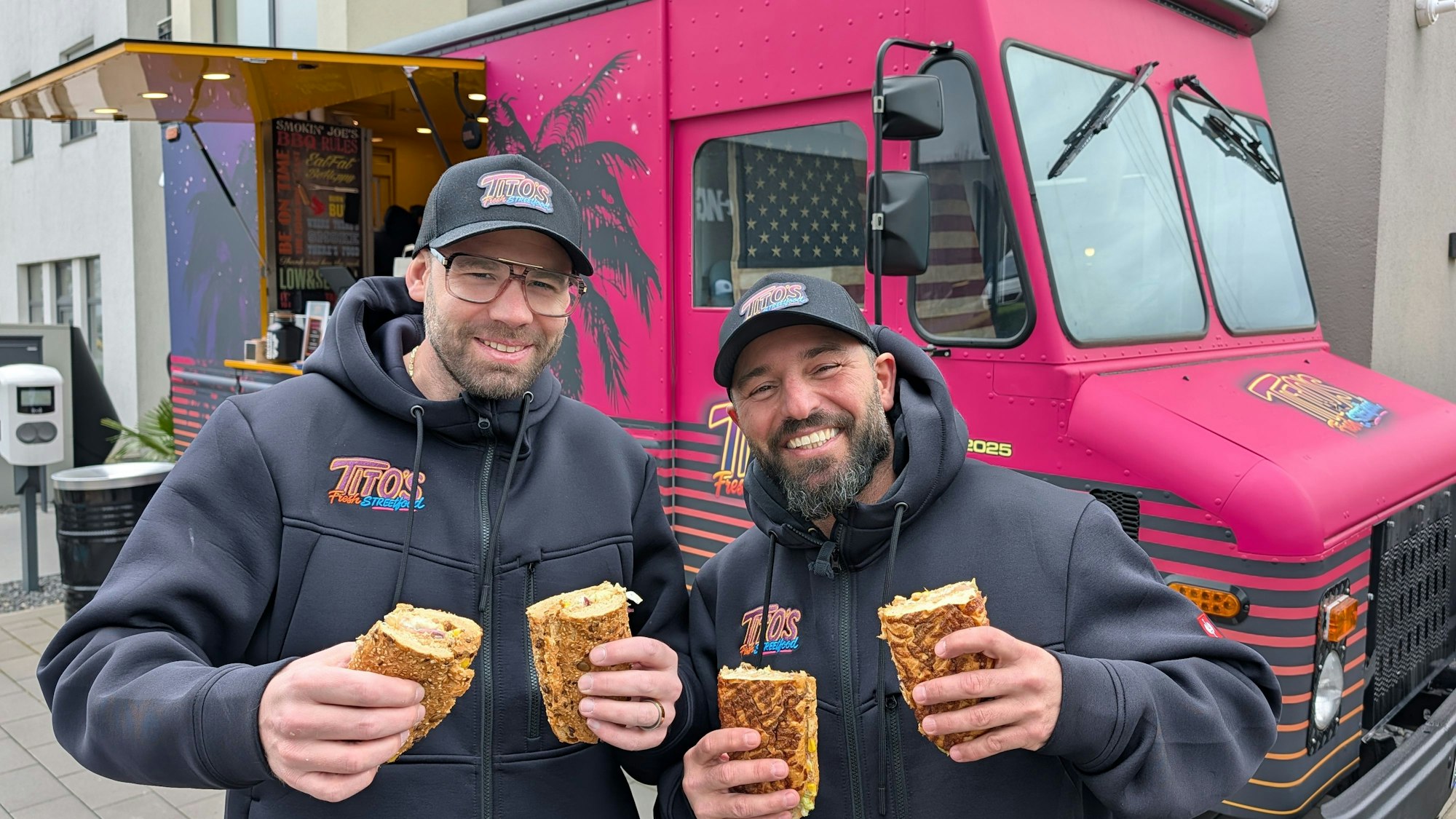 Das Foto zeigt die beiden Betreiber mit Baguettes vor dem Foodtruck.