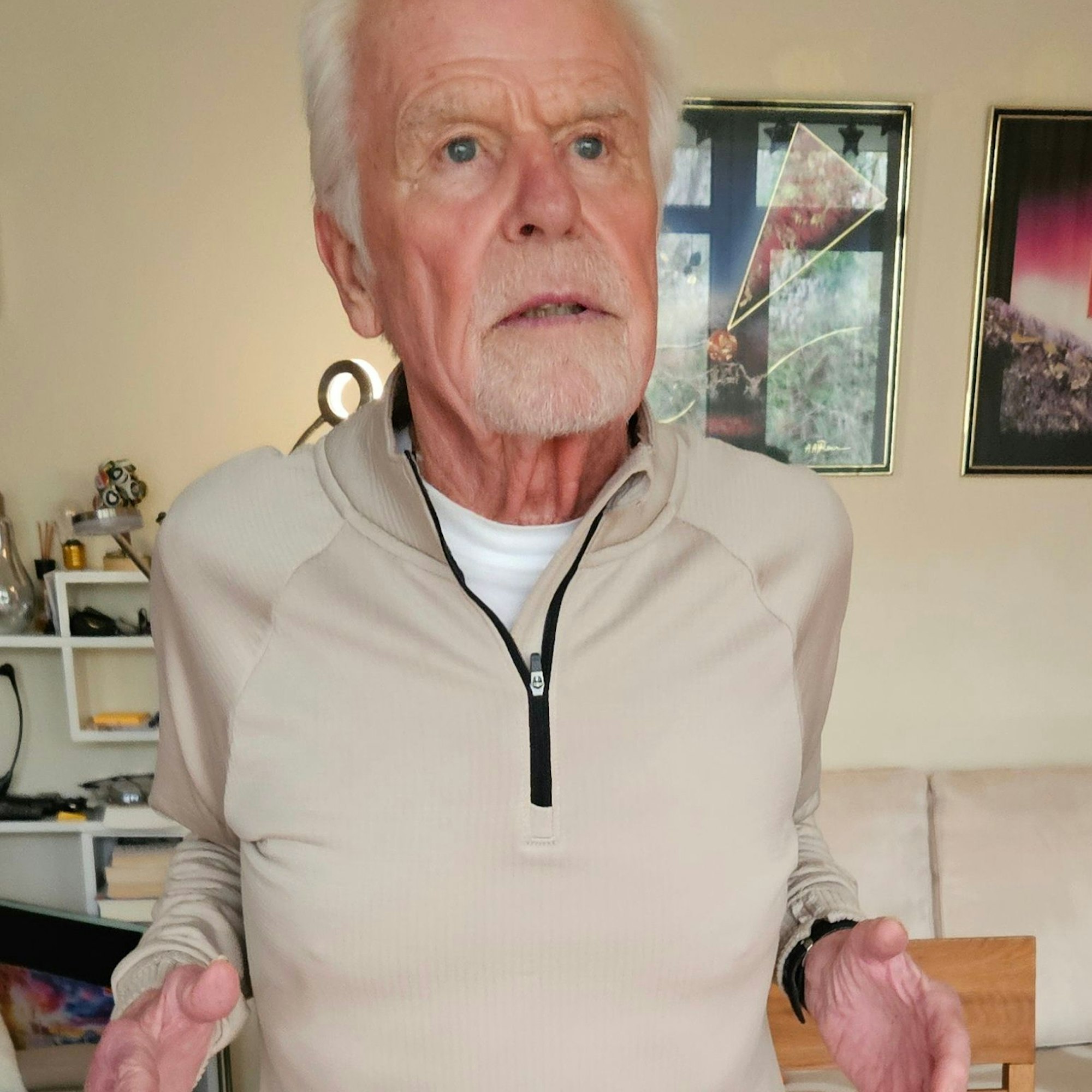 Ein Senior im Gymnastikanzug zieht die Schultern nach hinten.