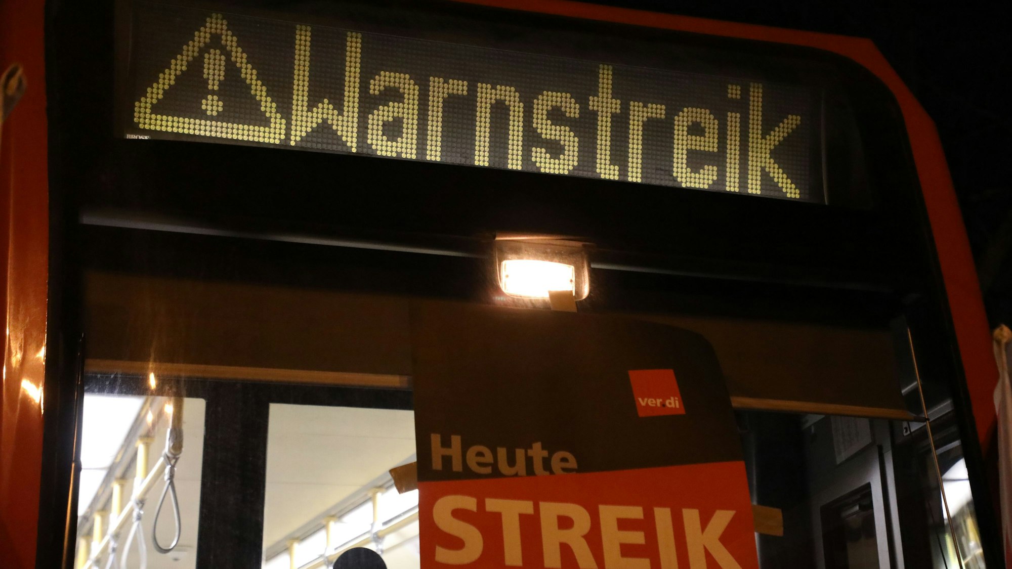 „Warnstreik“ steht auf der Anzeige einer Stadtbahn in Köln. Dort sollen Busse und Bahnen am Sonntag fahren - anders als in Teilen von NRW.