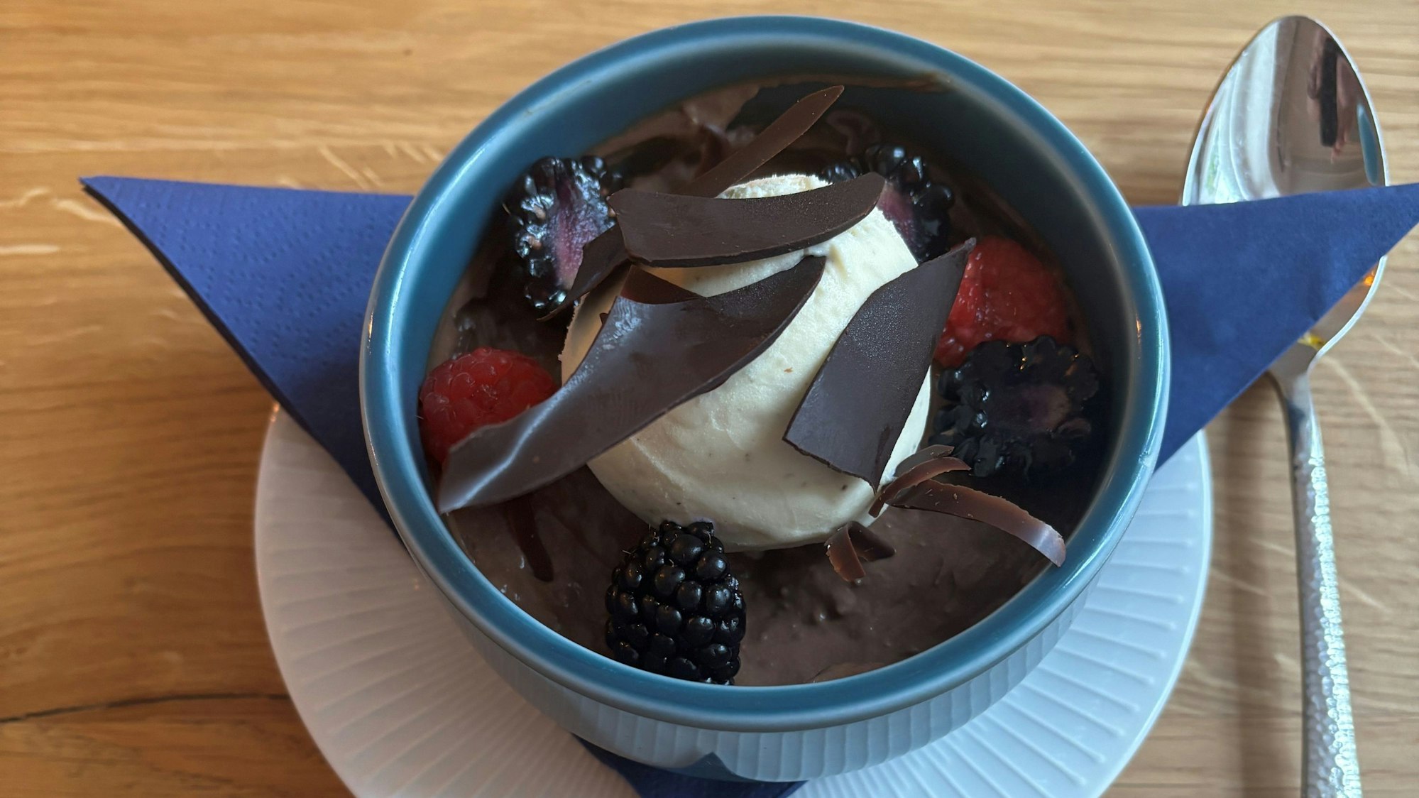 Das Bild zeigt eine Schüssel mit dem Pudding, darüber Eis, Beeren und Schokosplitter.