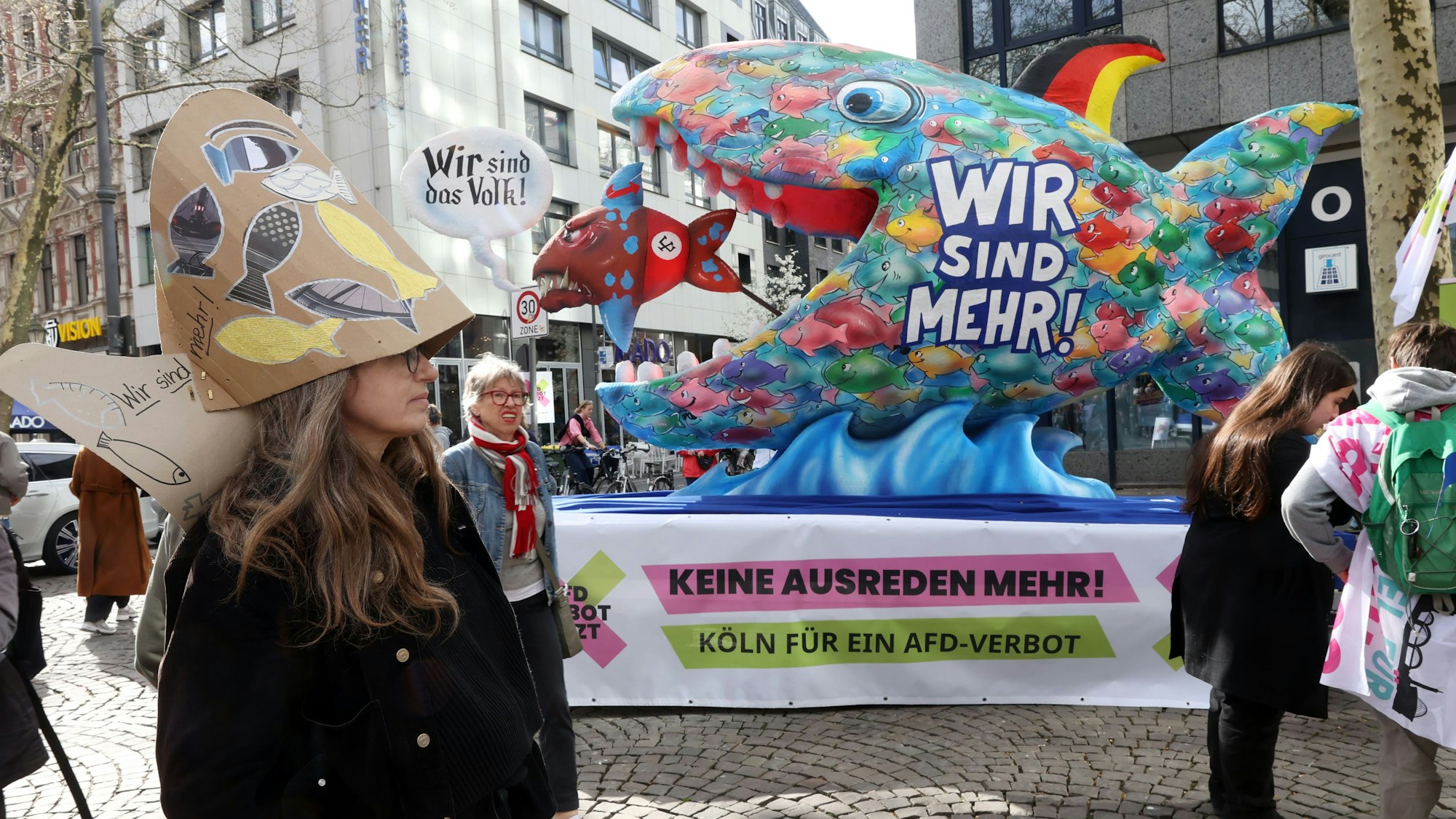 21.03.2026: Zum Internationalen Tag gegen Rassismus veranstalten verschiedene Gruppierungen eine Kundgebung auf dem Hohenzollernring. Bei der Versammlung „Für Demokratie – gegen Rassismus“ werden 10.000 Teilnehmende erwartet. Neben der Bühne und Infoständen soll am Hohenzollernring dann auch ein Wagen aus dem Düsseldorfer Rosenmontagszug 2024 von Jaques Tilly stehen: Zu sehen ist darauf ein großer, bunter Fisch mit der Aufschrift „Wir sind mehr“, der einen kleineren Fisch mit der Sprechblase „Wir sind das Volk“ verspeist. Foto: Martina Goyert
