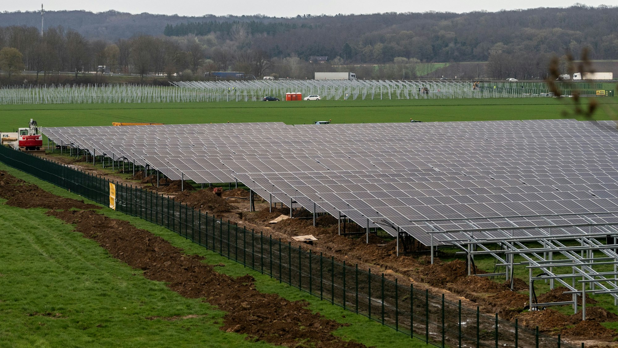 Hinter eine Zaum werden gerade Solarpaneele montiert.