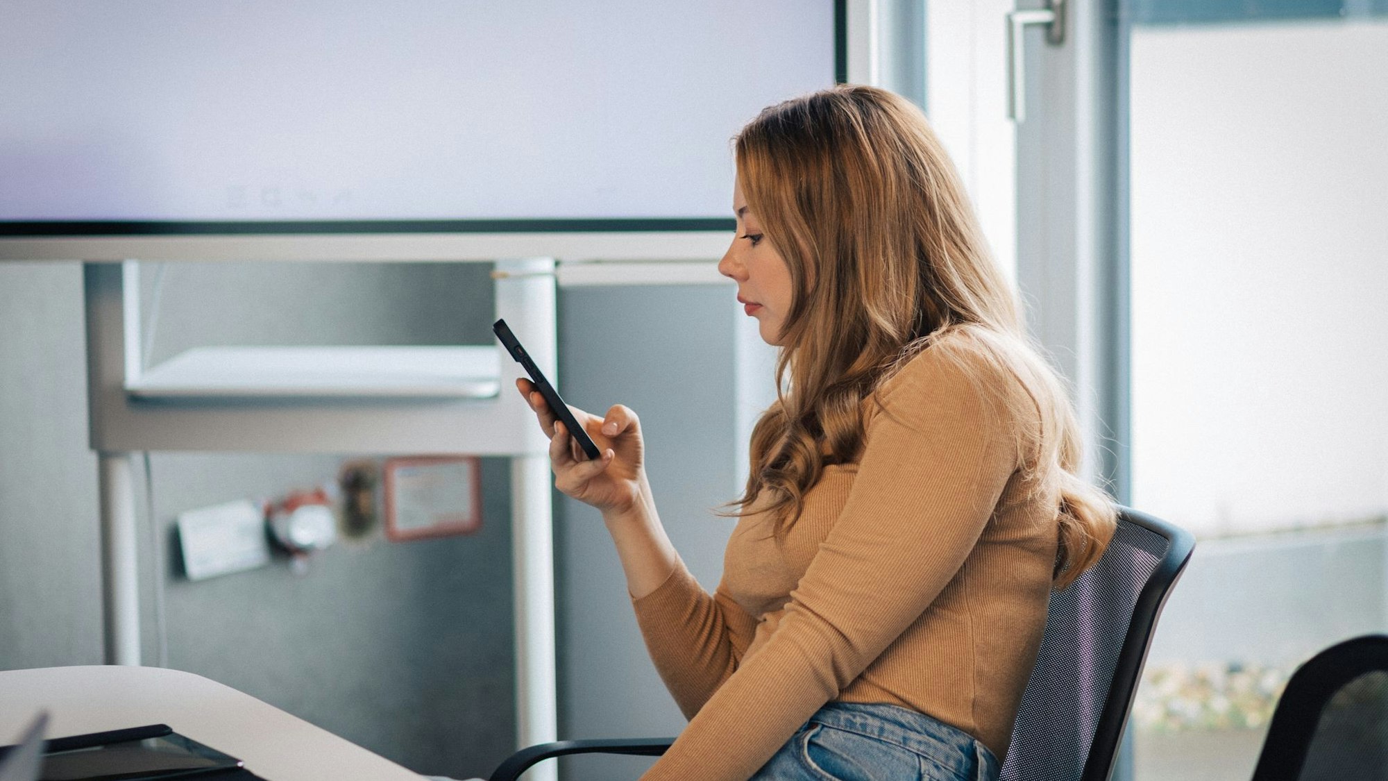 Junge Frau mit Smartphone im Büro