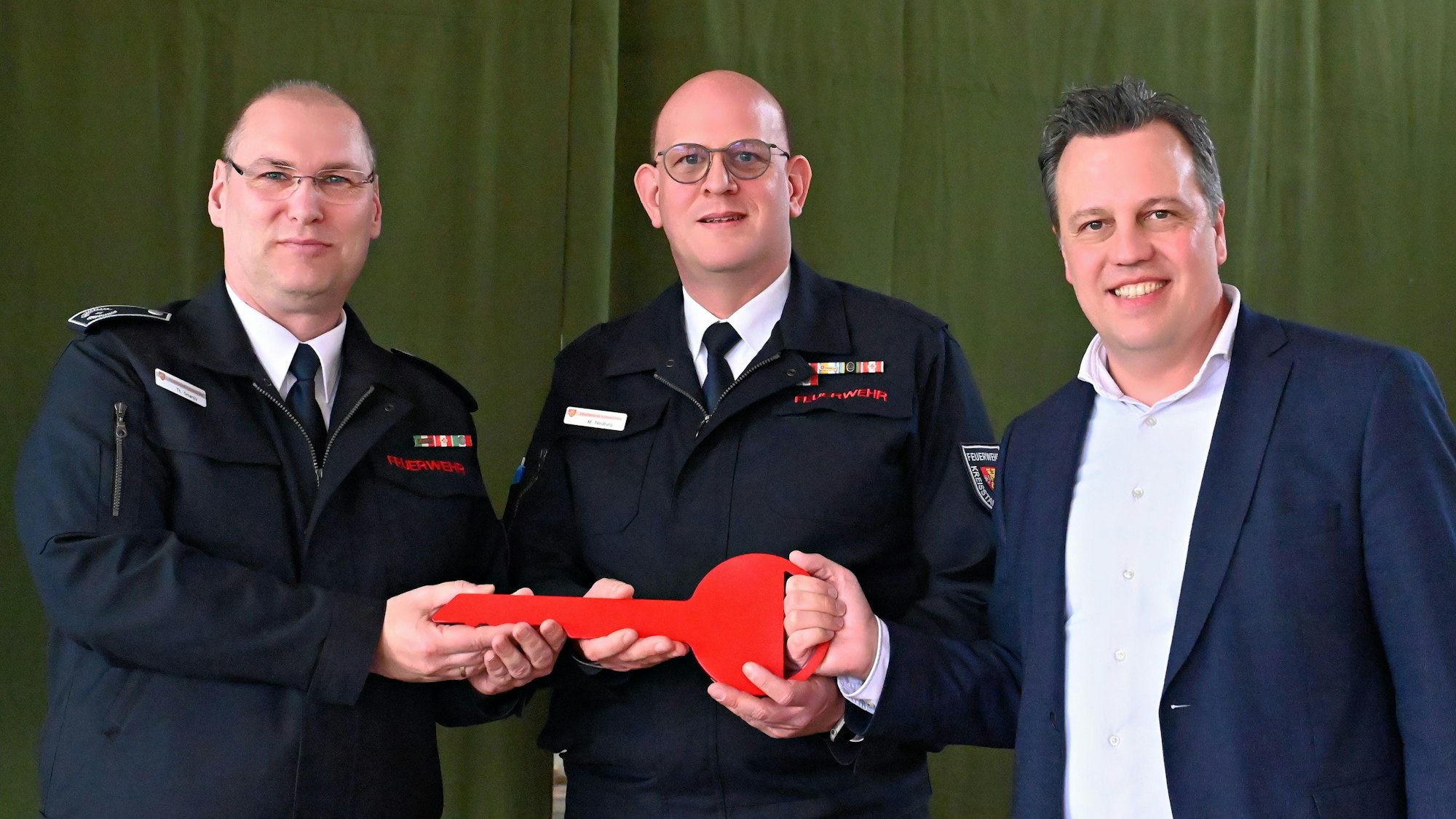 Thomas Smarsly (v.l.) und Markus Neuburg halten einen großen roten Schlüssel, neben ihren steht Bürgermeister Sacha Reichelt.