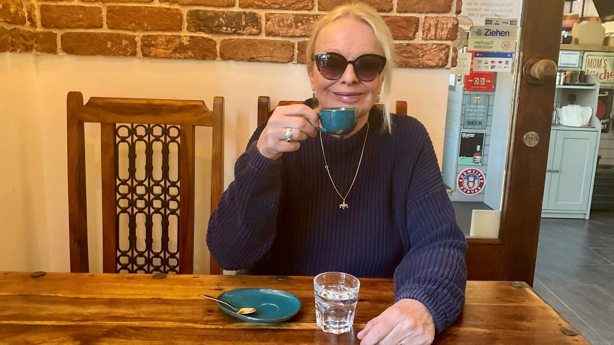 Yvonne Eckhardt sitzt mit einem Kaffee in der Hand an einem Tisch.