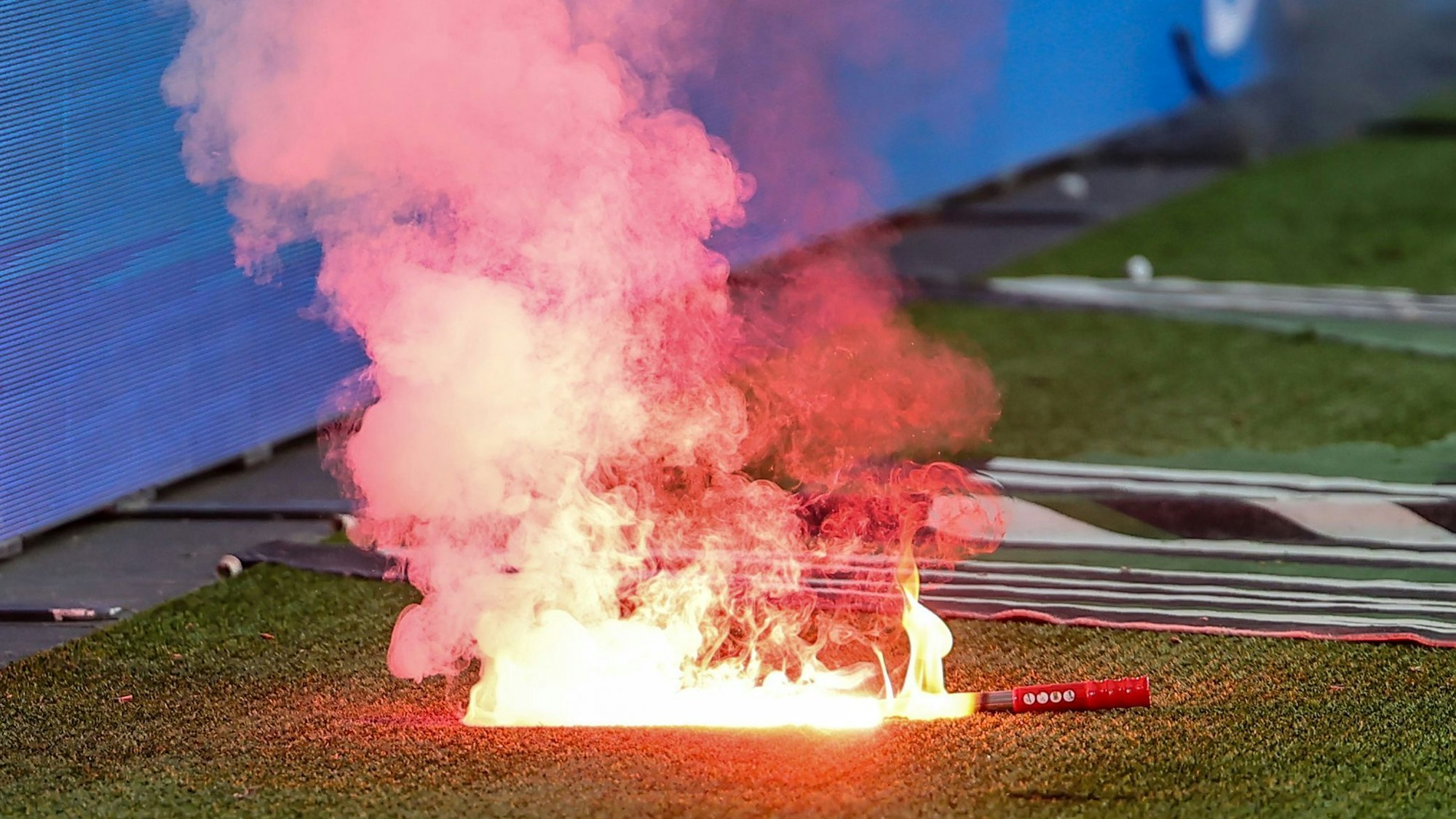 Eine Leuchtfackeln brennt an einem Fußballplatz.