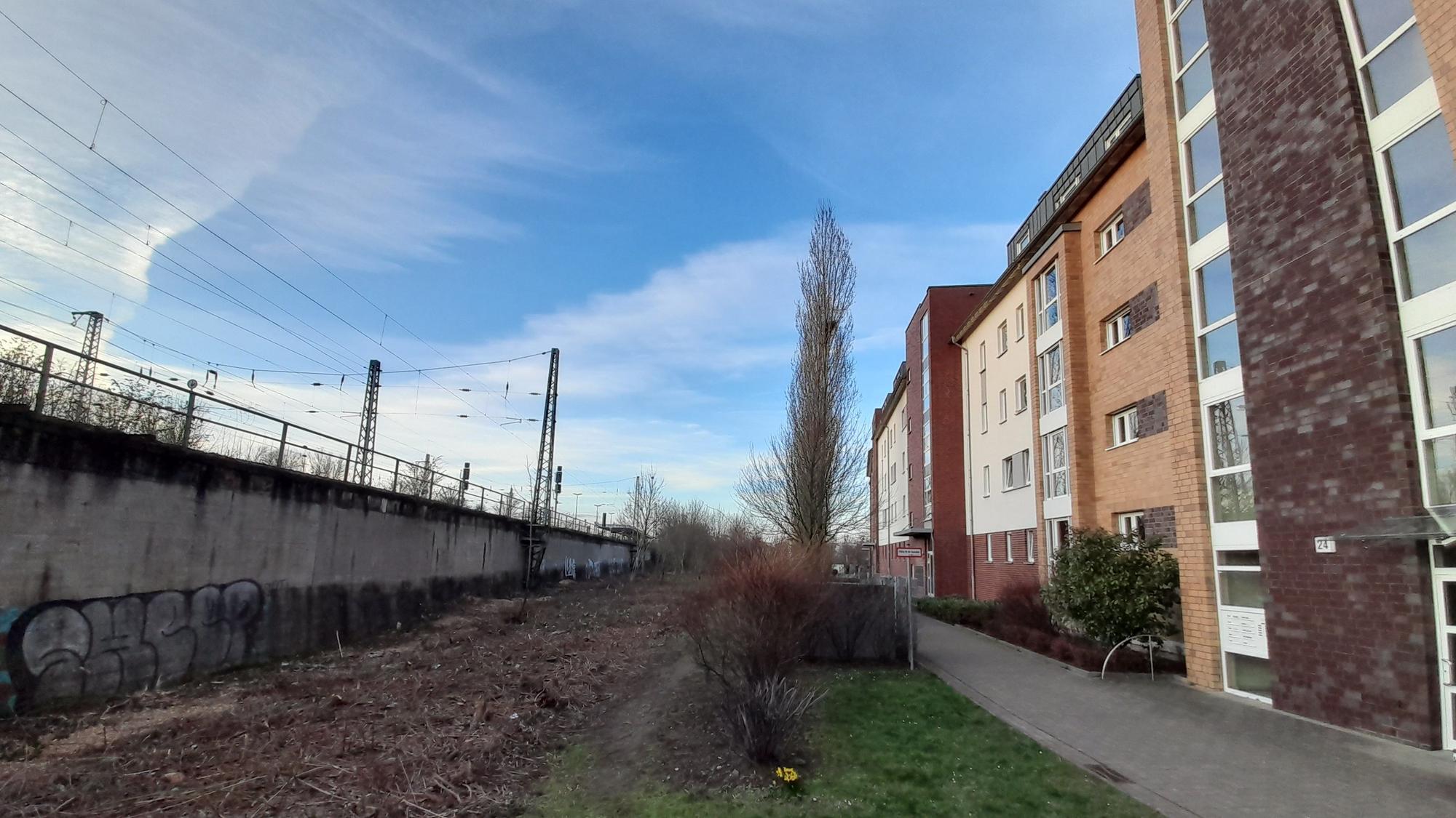 Neben Häuserblöcken verläuft ein Bahndamm.