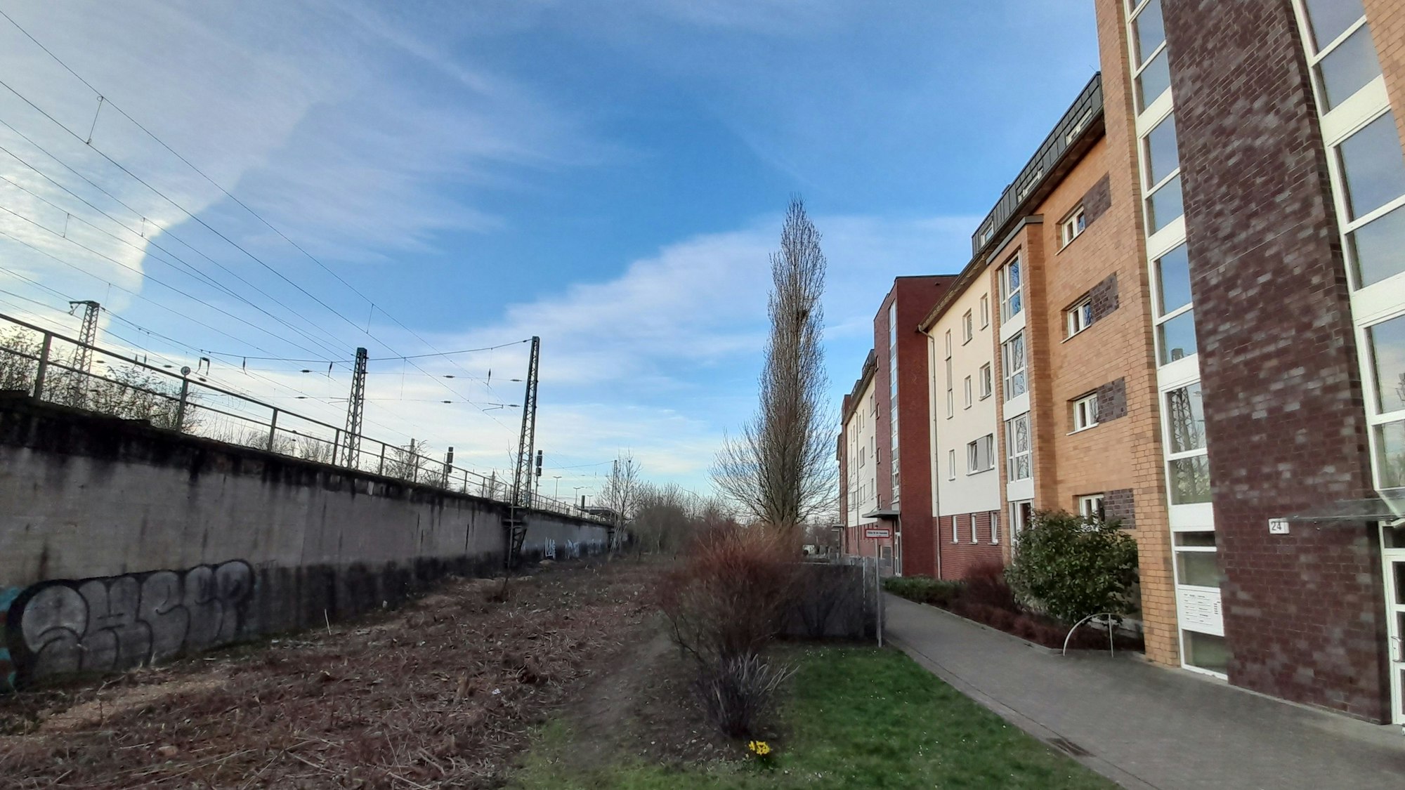 Neben Häuserblöcken verläuft ein Bahndamm.