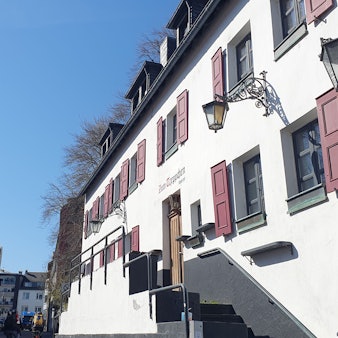 Ein großes altes Haus mit roten Fensterläden ist zu sehen.