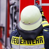Ein Feuerwehrmann holt eine Leiter vom Dach eines Einsatzfahrzeugs. (Symbolbild)