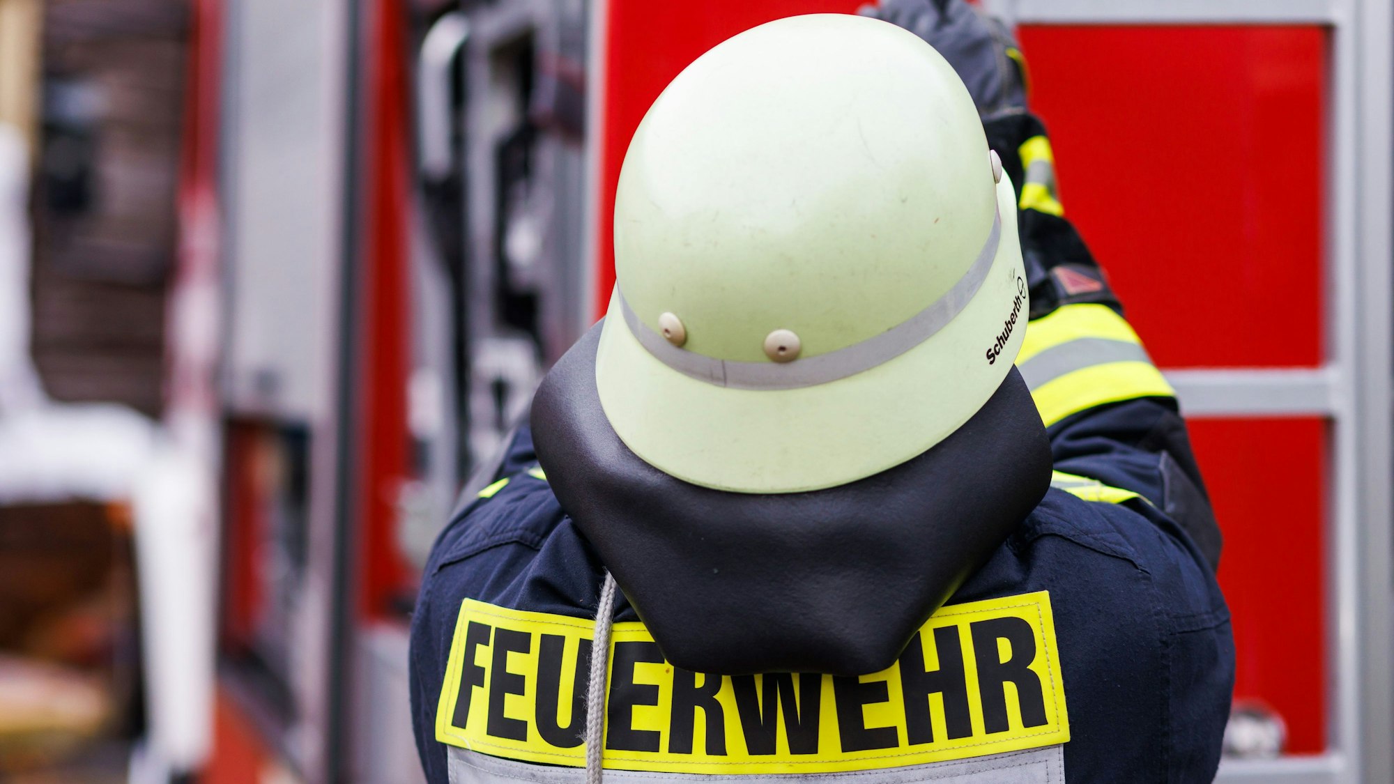 Ein Feuerwehrmann holt eine Leiter vom Dach eines Einsatzfahrzeugs. (Symbolbild)