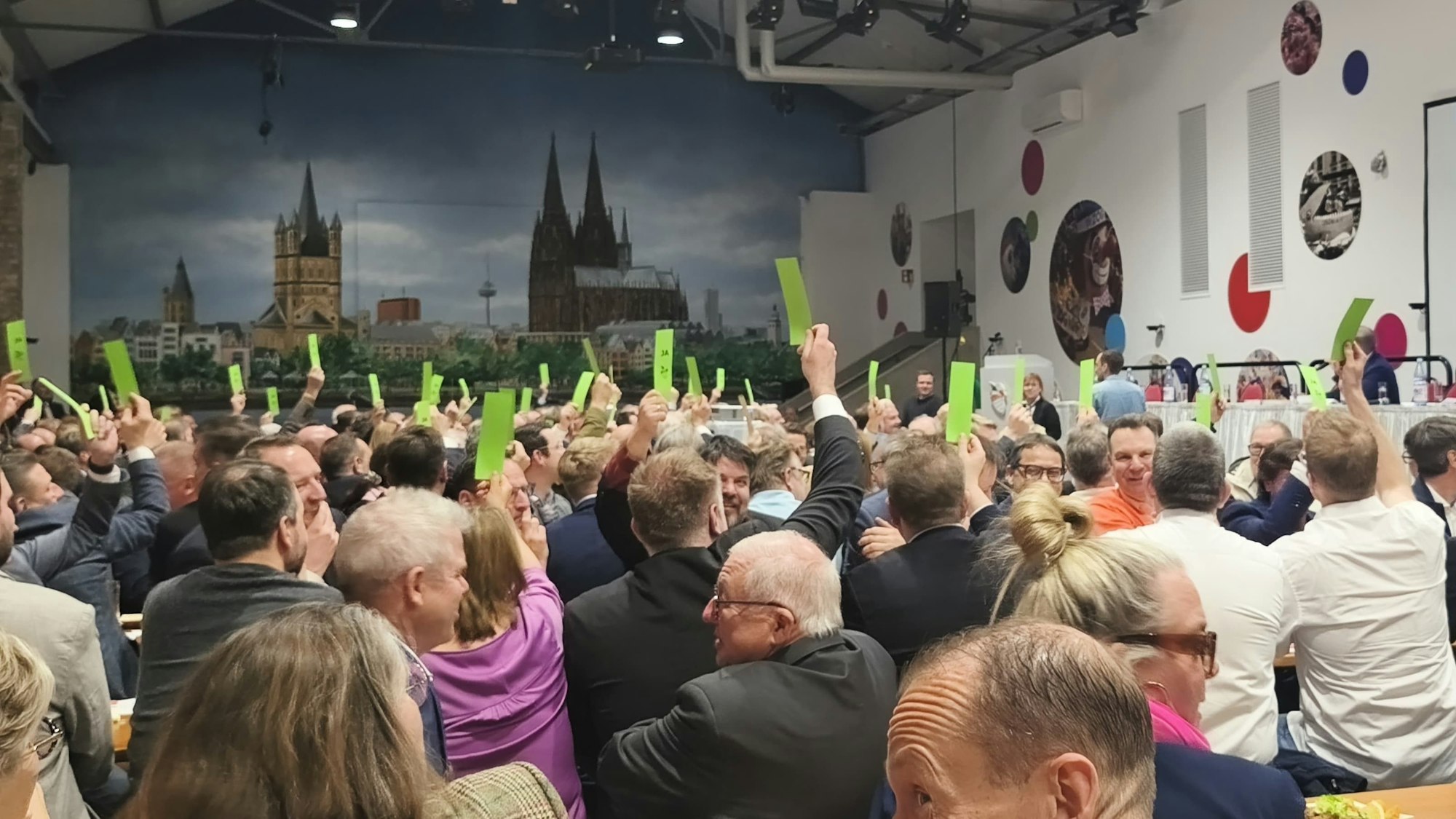 Mitglieder heben die Abstimmungskarten in die Höhe.