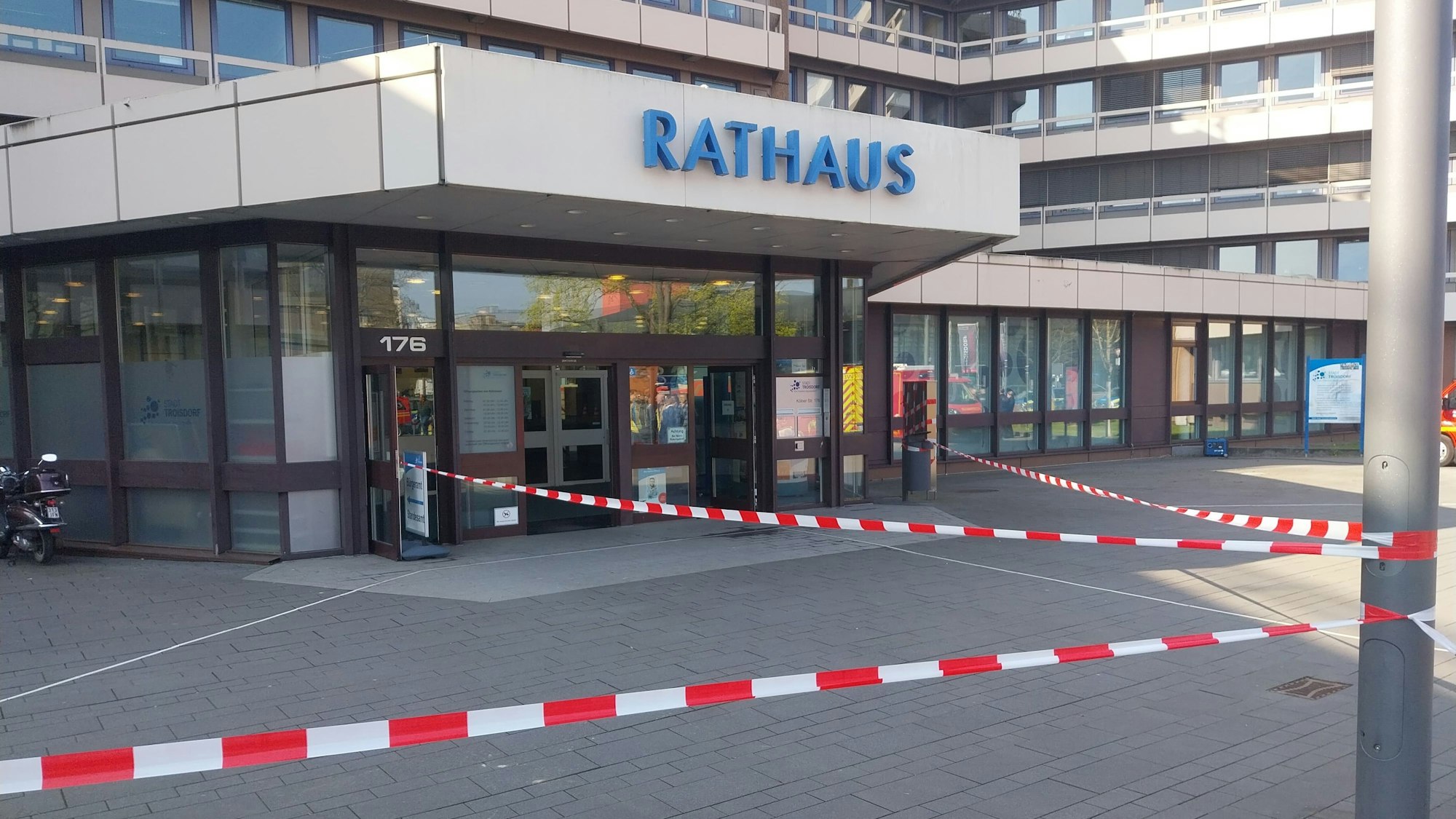 Rot-Weißes Absperrband hängt vor dem Eingangsbereich des Troisdorfer Rathauses.