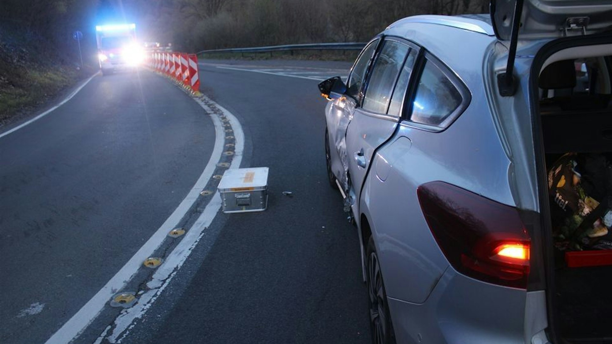 Ein Unfallauto steht in der Abenddämmerung auf einer Straße.