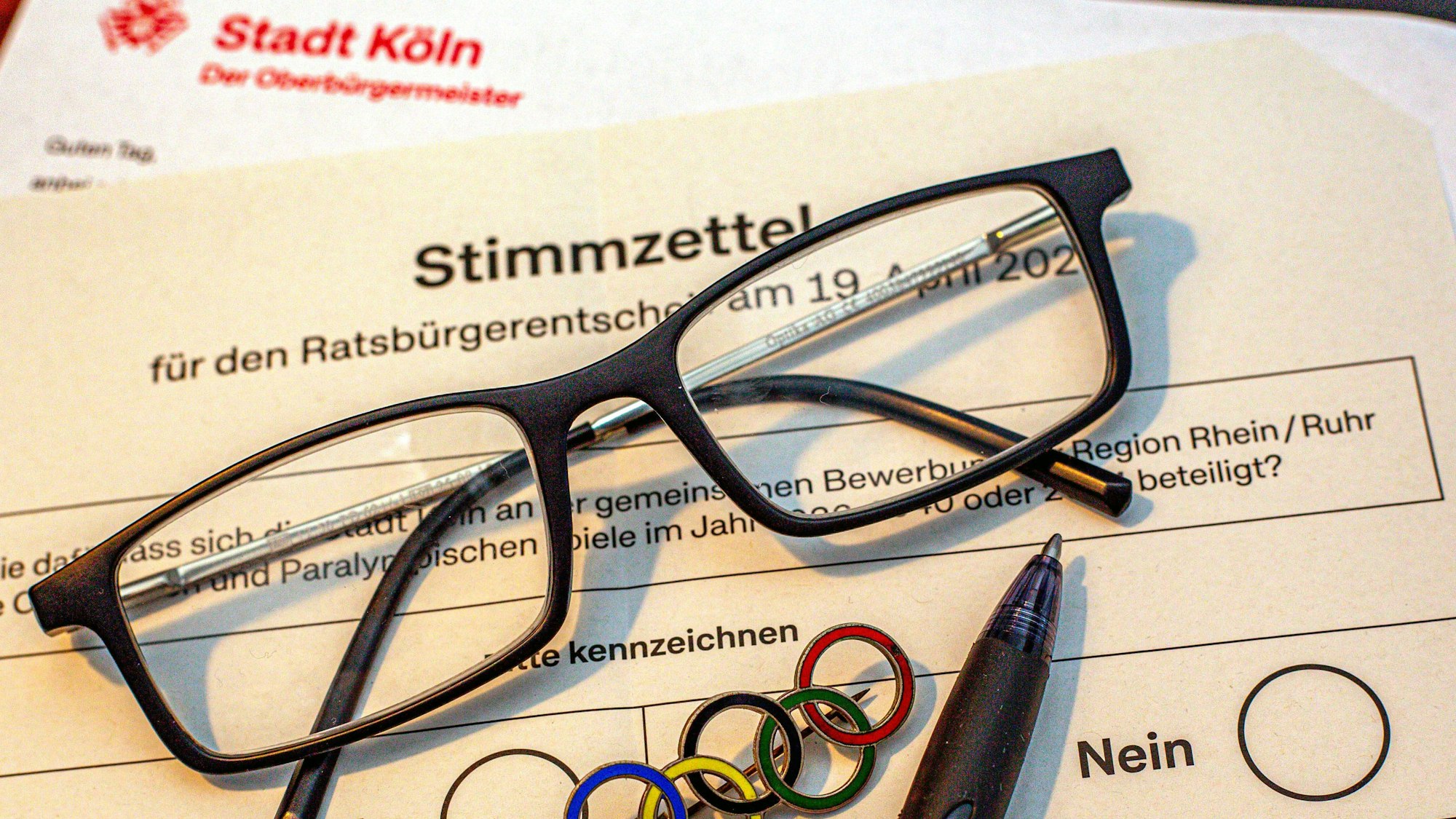 Unterlagen zur Abstimmung über die Olympischen Spiele in Köln und der Region Rhein/Ruhr liegen auf einem Tisch. Bis zum 19. April 2026 kann die Bevölkerung darüber abstimmen, ob sich Köln an der Bewerbung für die Olympischen und Paralympischen Spiele in der Region Rhein-Ruhr beteiligen soll. Symbolbild Bürgerentscheid Olympia *** Documents for the vote on the Olympic Games in Cologne and the Rhine-Ruhr region are on a table Until April 19, 2026, the population can vote on whether Cologne should participate in the bid for the Olympic and Paralympic Games in the Rhine-Ruhr region Symbolic image of the referendum on the Olympics