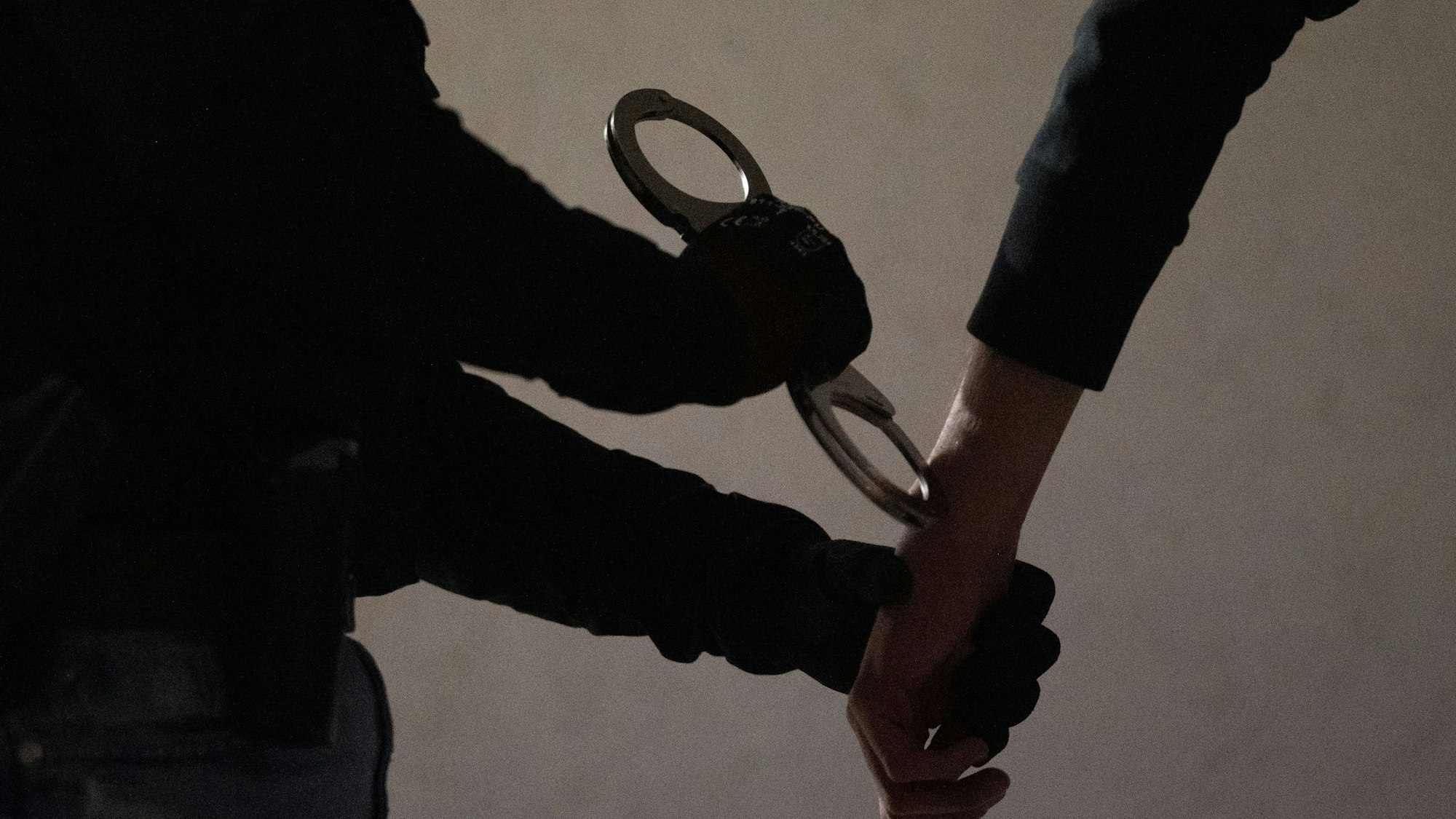 Eine Polizistin legt einem Mann Handschellen an.