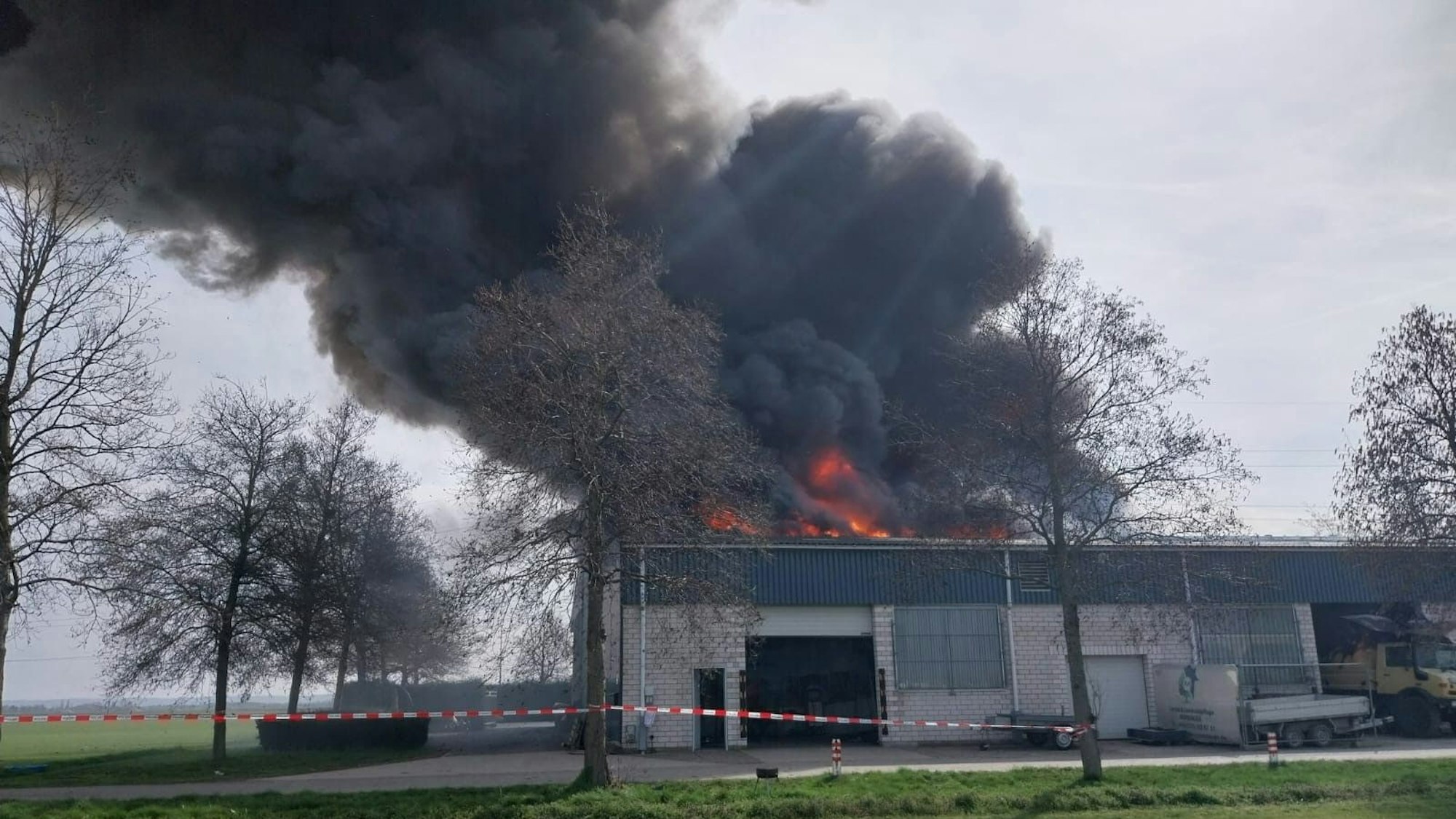 Dicke, schwarze Rauchwolken steigen aus der Lagerhalle.