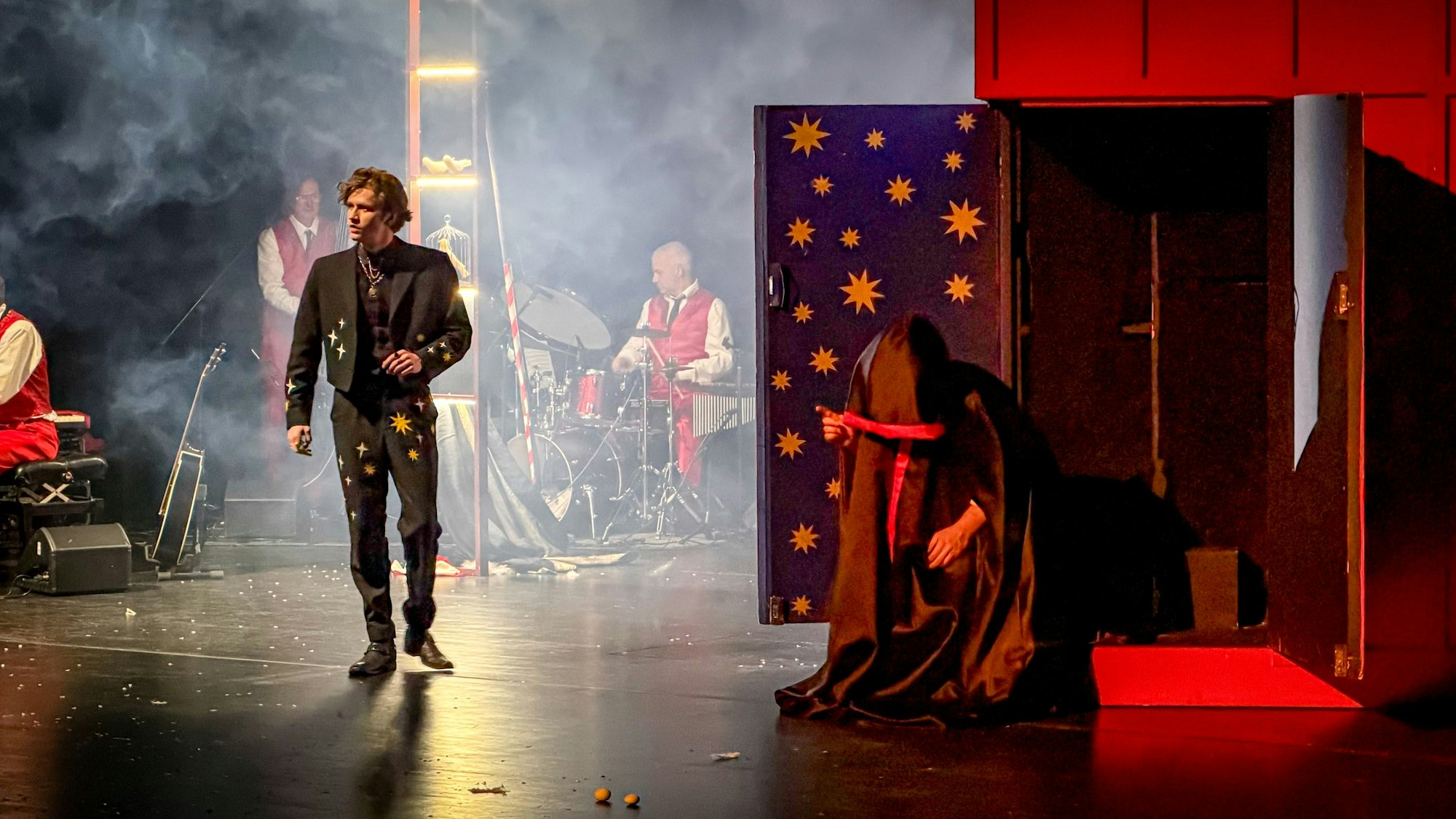 Ein Schauspieler geht über eine Bühne, im Hintergrund ein Schlagzeuger.