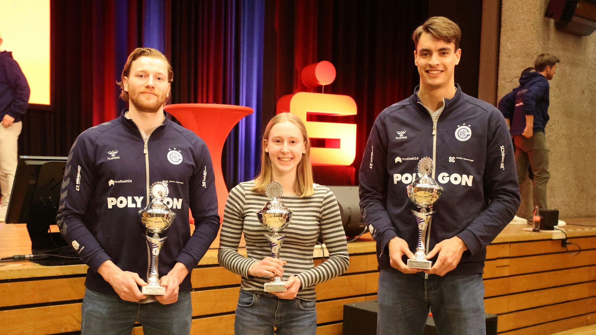 Drei Sportler mit ihren Pokalen.