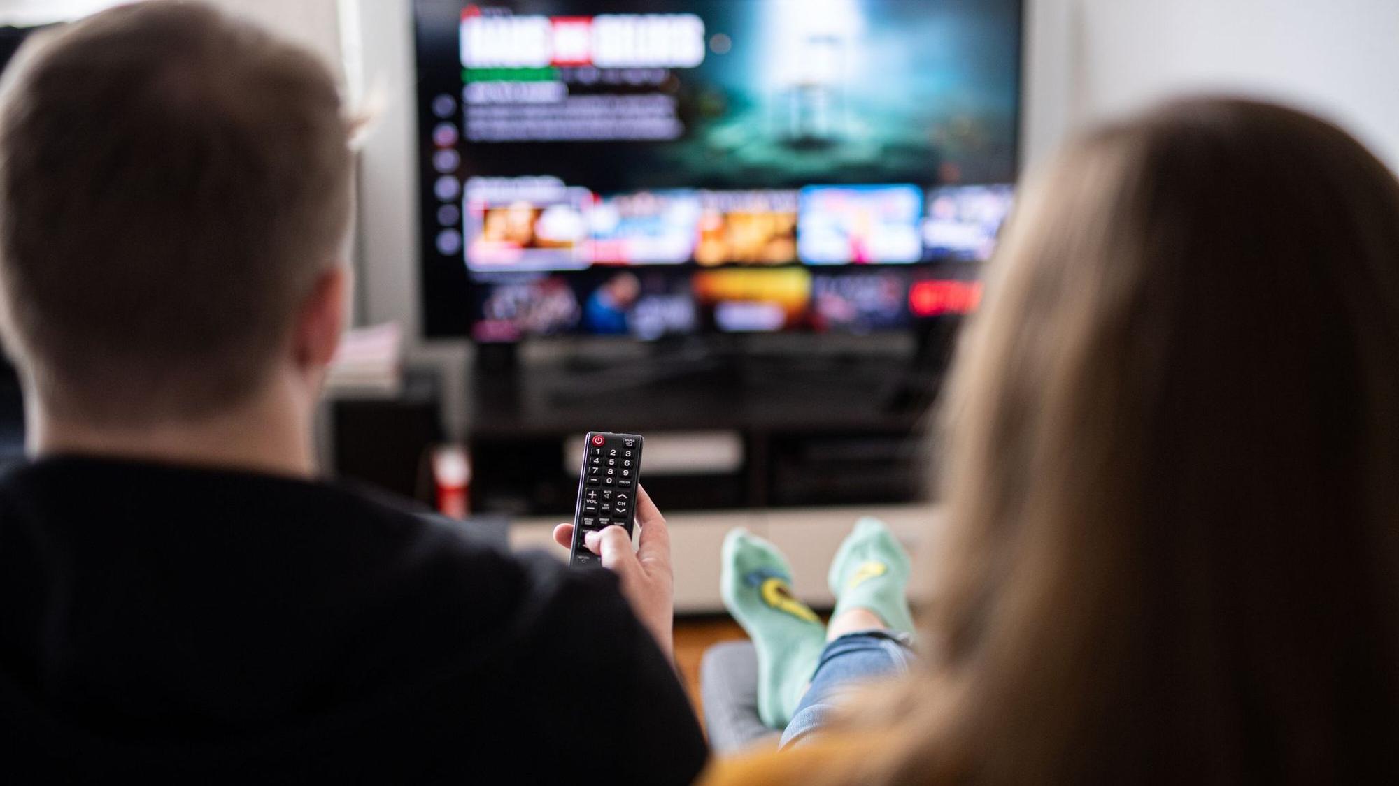 Paar sitzt vor einem Fernseher