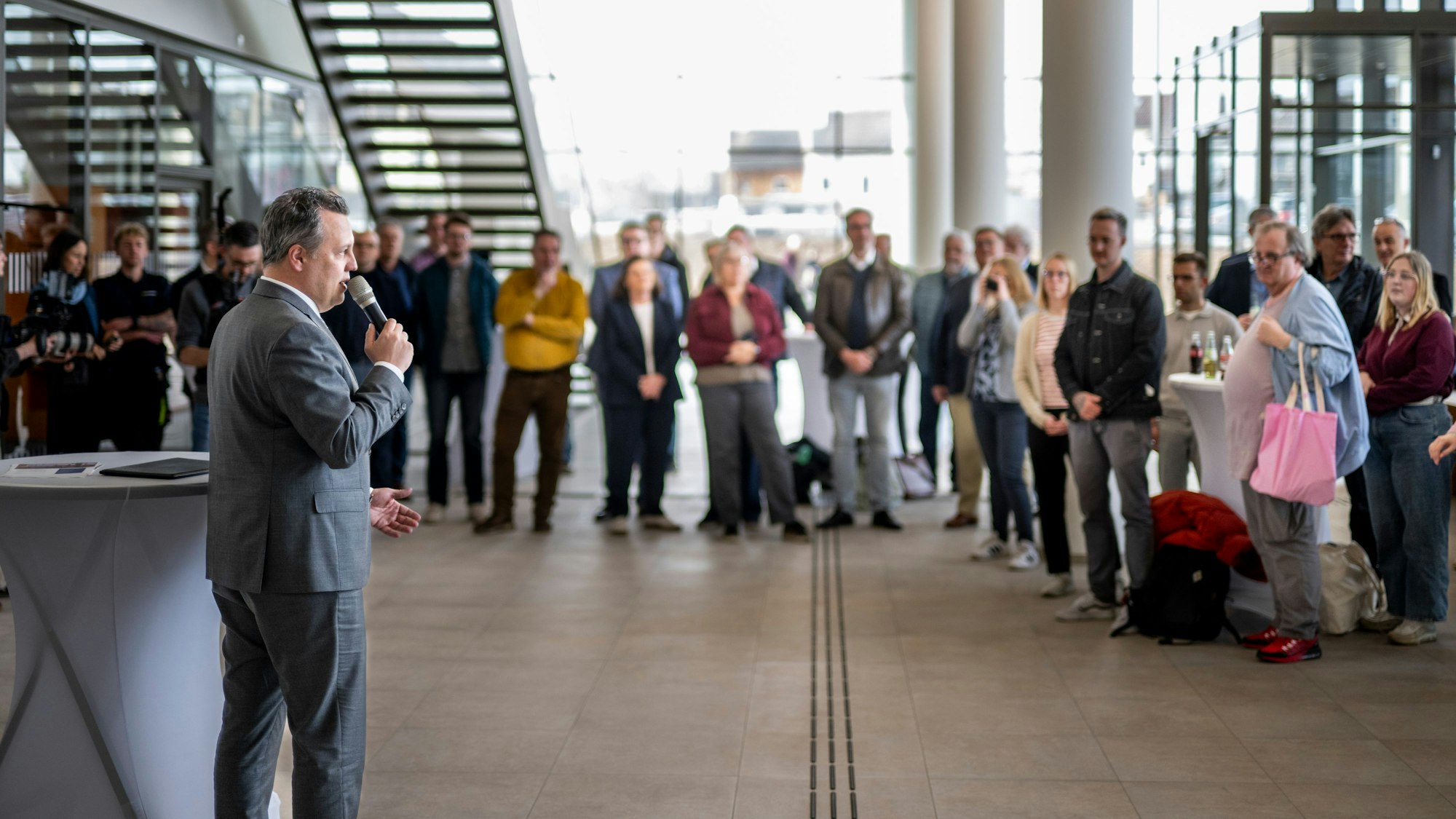 Bürgermeister Sacha Reichelt steht vor einer Gruppe Menschen und spricht in ein Mikrofon.