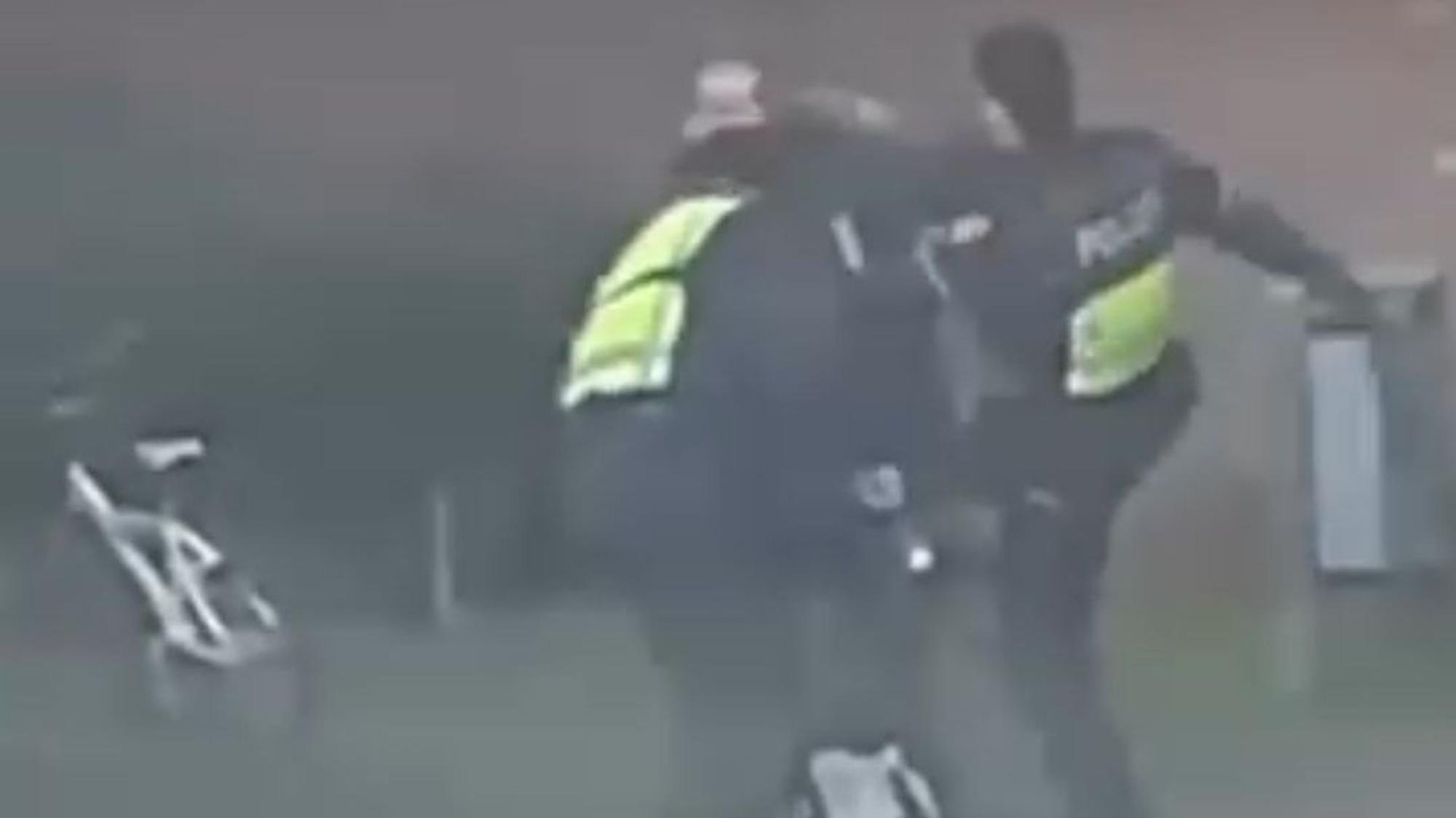 Zu sehen sind zwei Polizisten und ein Mann auf einer unscharfen Video-Aufnahme.