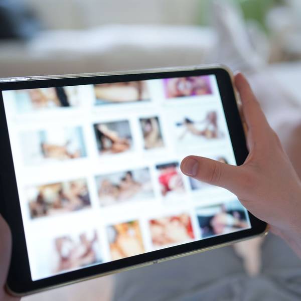 Ein junger Mann schaut sich auf einem Smartphone eine Porno-Internetseite an (gestellte Szene).