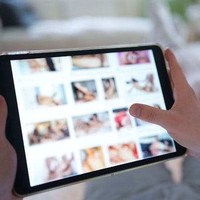 Ein junger Mann schaut sich auf einem Smartphone eine Porno-Internetseite an (gestellte Szene).