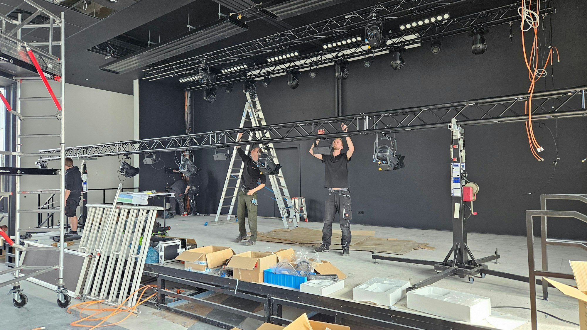 Auf der Bühne arbeiten zwei Männer an der Beleuchtung.
