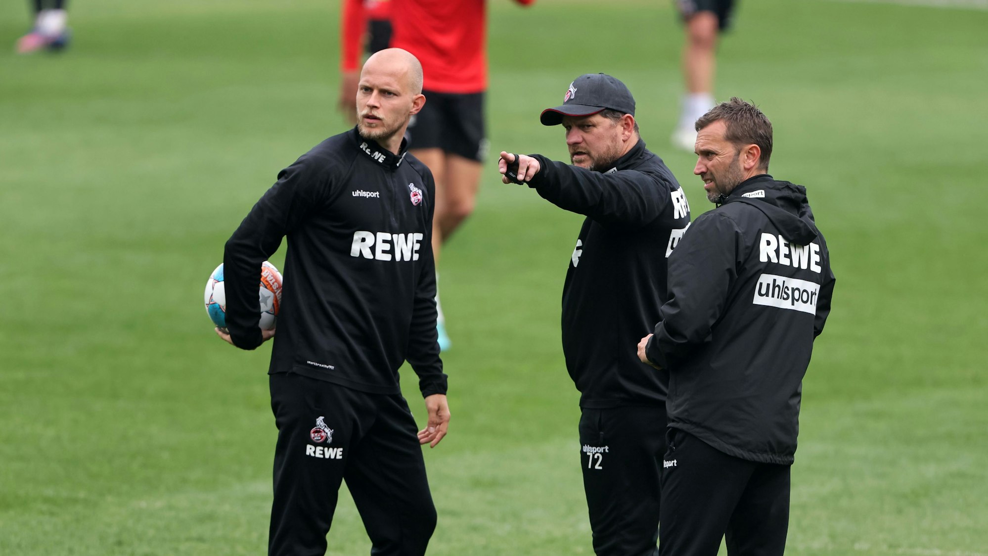 Steffen Baumgart zeigt René Wagner und André Pawlak etwas auf dem Trainingsplatz.