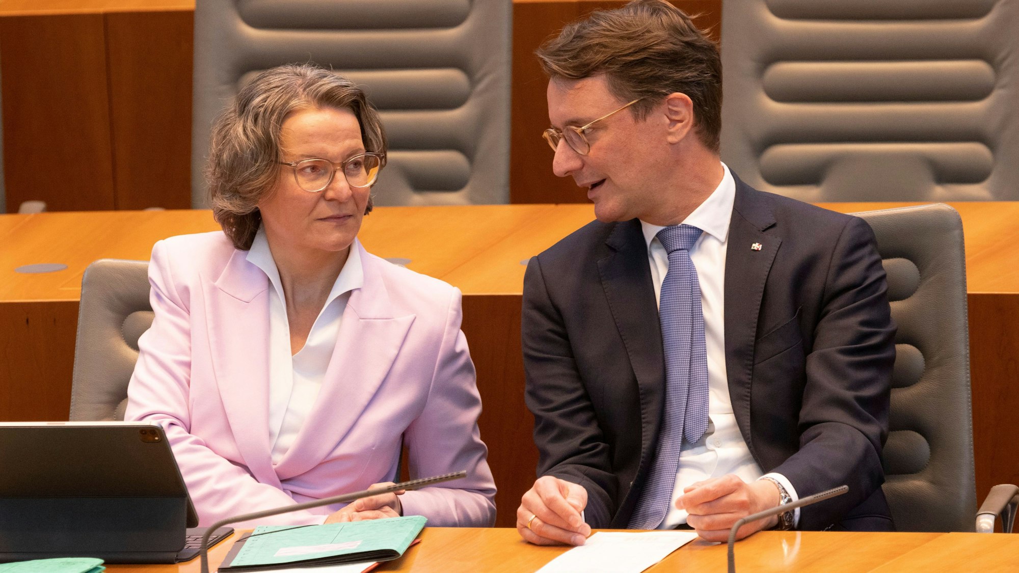 Ina Scharrenbach (CDU), Ministerin für Heimat, Kommunales, Bau und Gleichstellung von NRW, und Hendrik Wüst (CDU), Ministerpräsident von NRW, unterhalten sich im Plenum des Landtags.